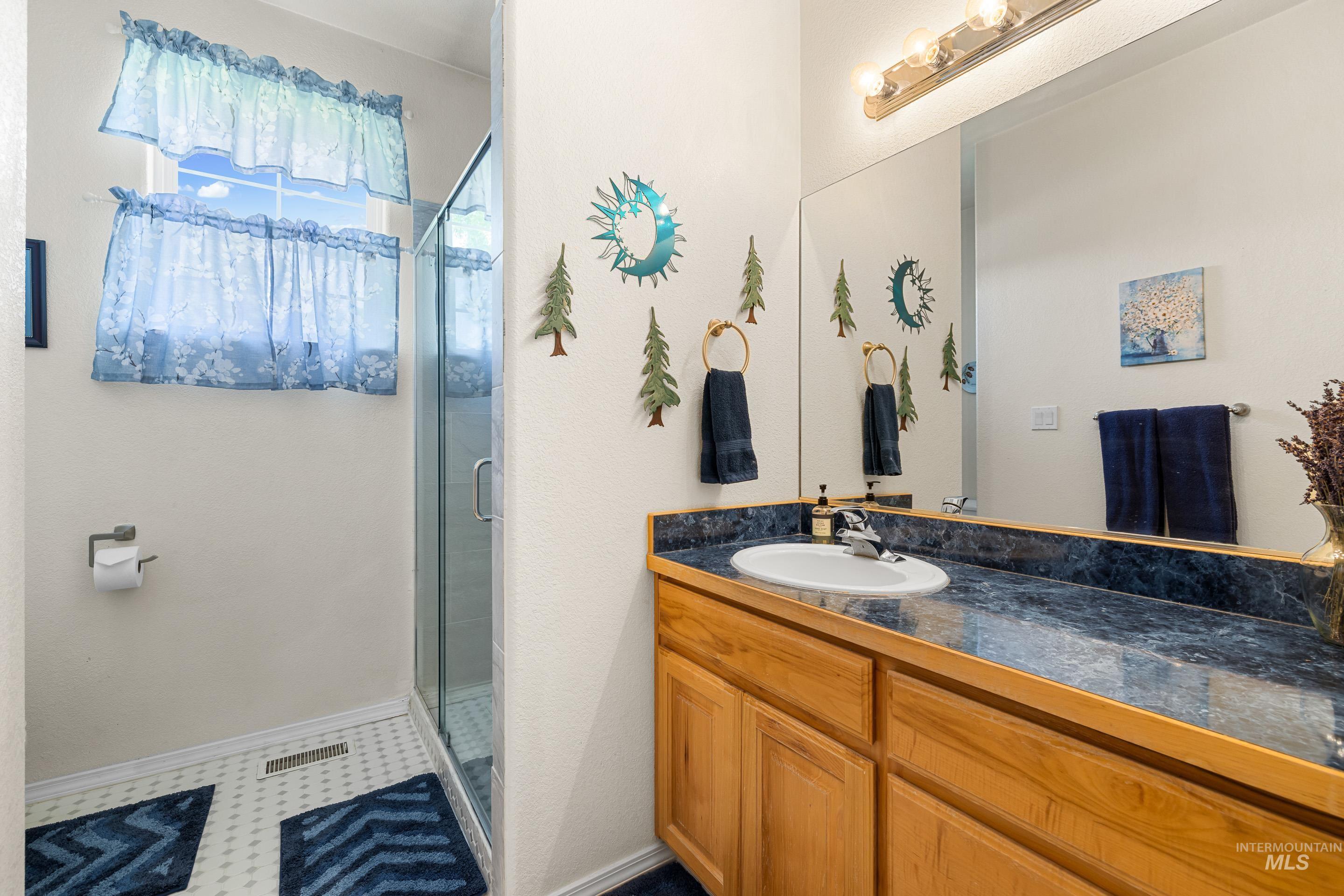 Full bathroom featuring a stall shower, vanity, and dark flooring
