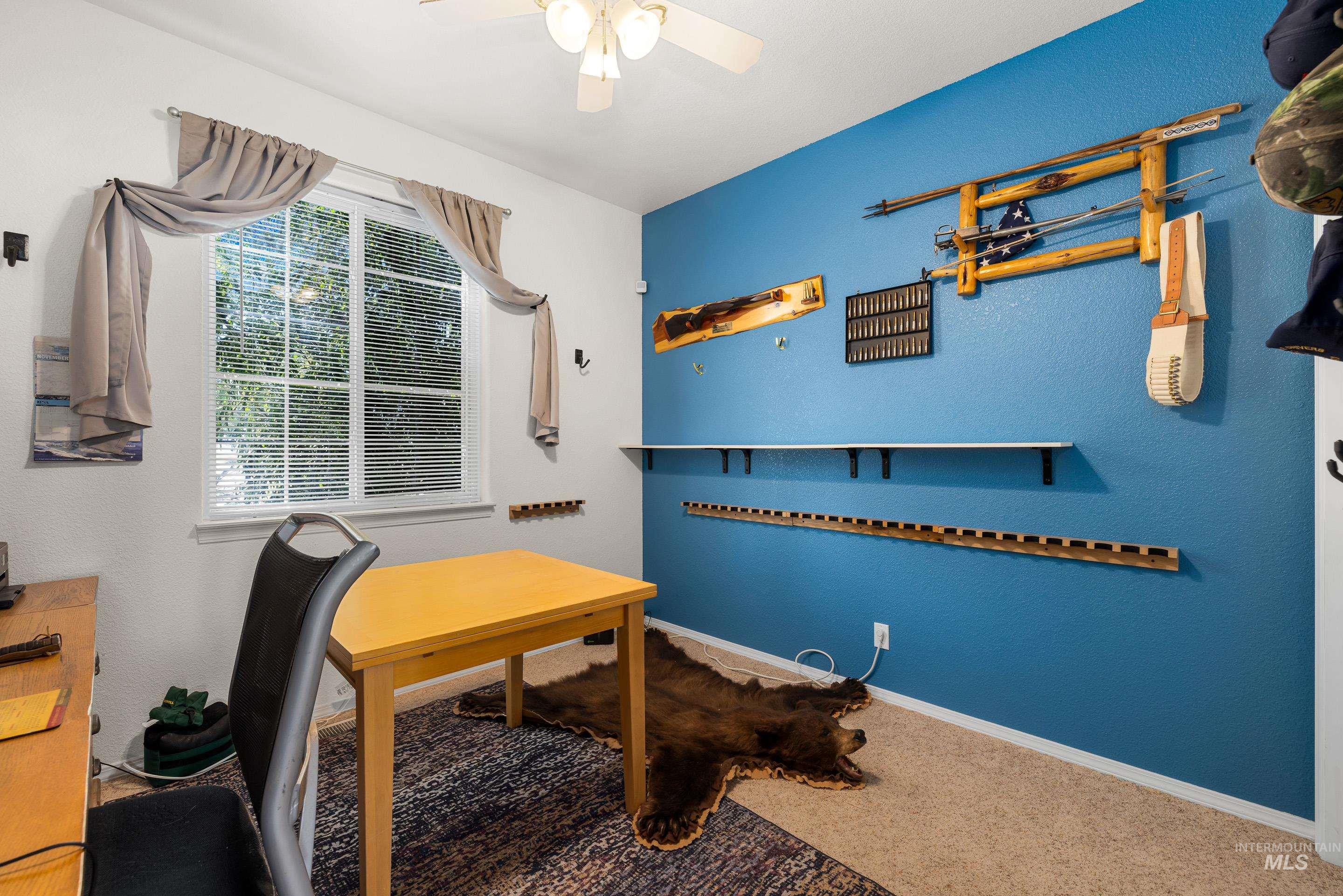 Office area with carpet, a textured wall, and ceiling fan