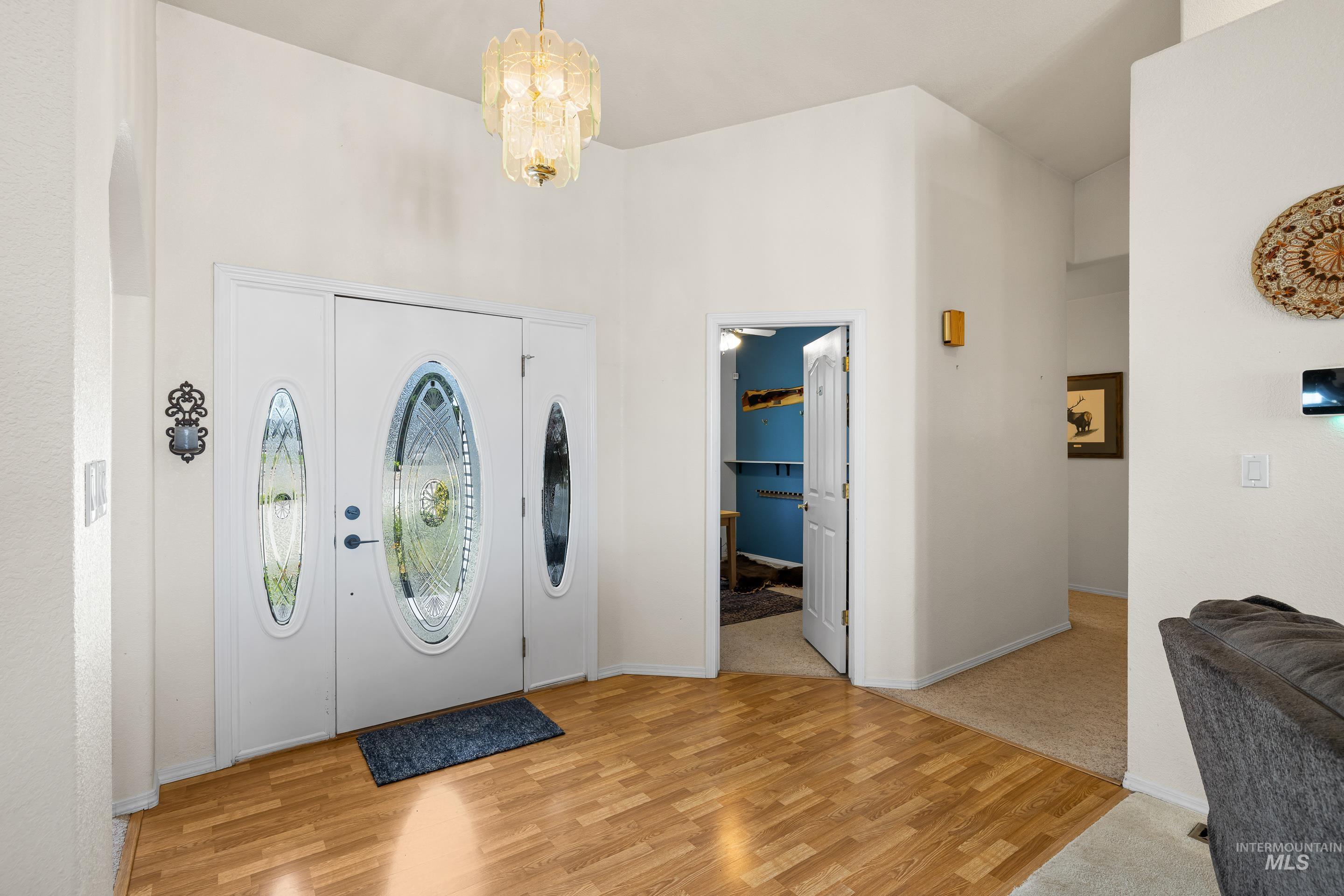 Entryway featuring light wood finished floors, a chandelier, and a towering ceiling