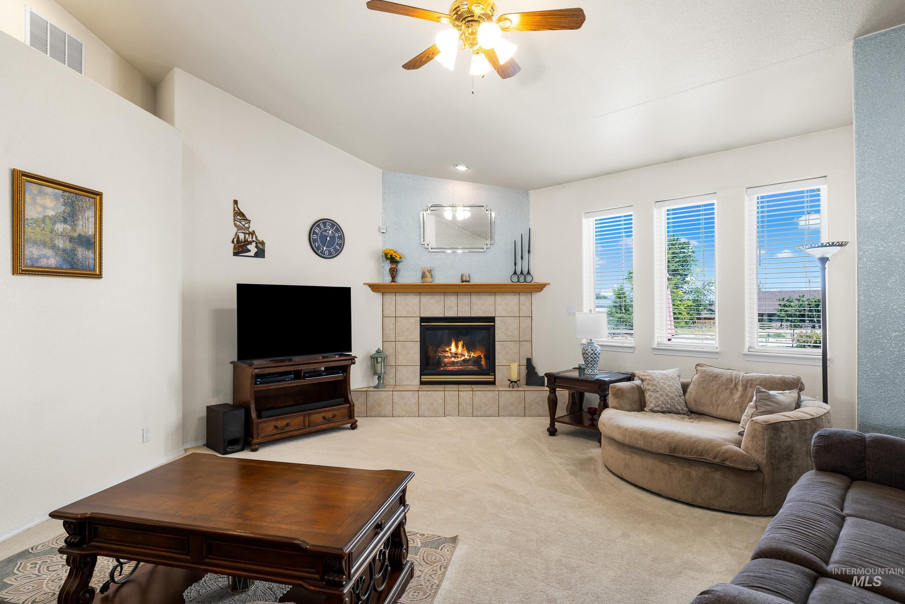 Carpeted living area featuring a fireplace and ceiling fan