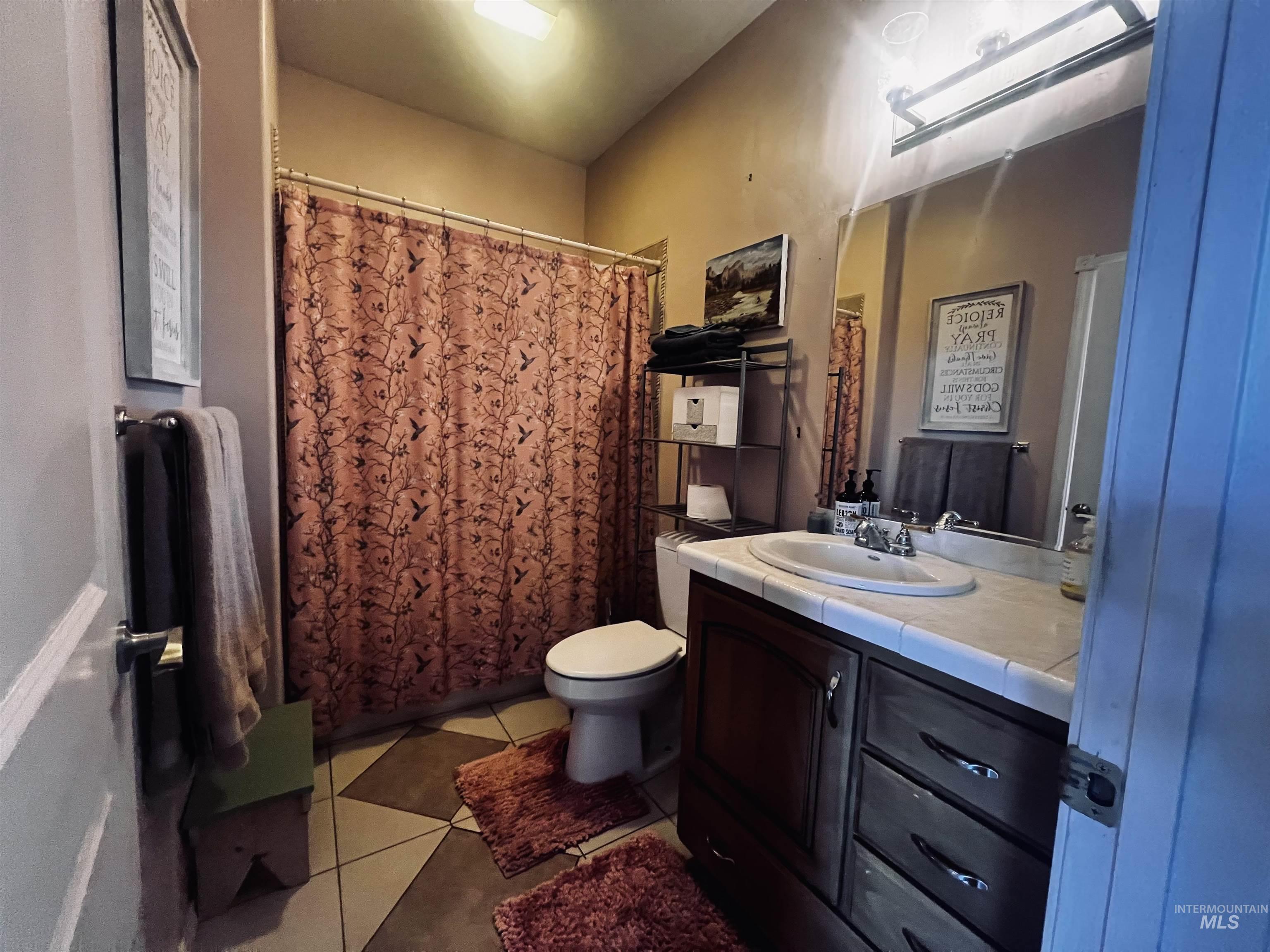 Full bath featuring light tile patterned floors, vanity, and a shower with curtain