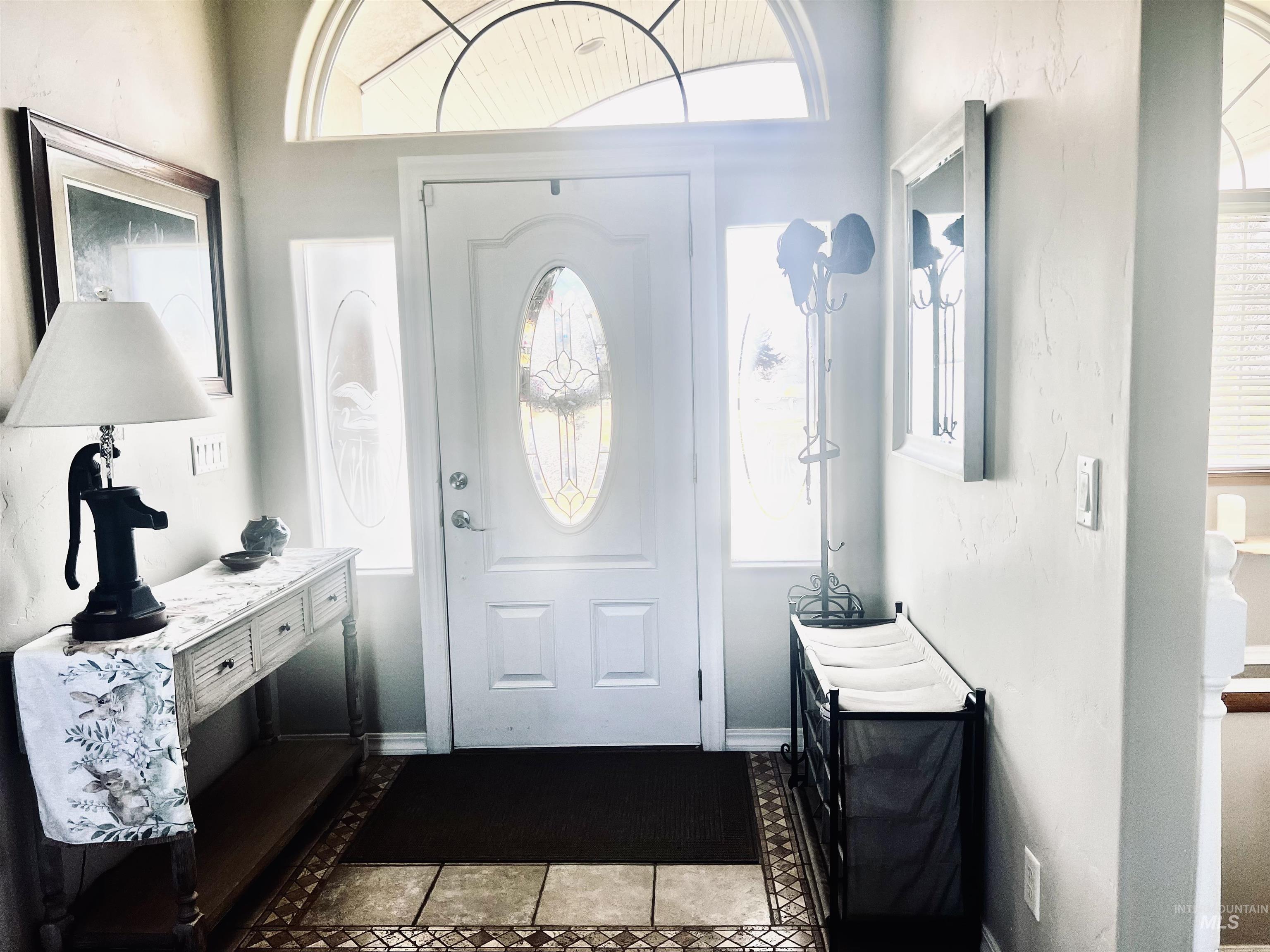 Foyer entrance with dark tile patterned flooring, healthy amount of natural light, and inlaid floor details