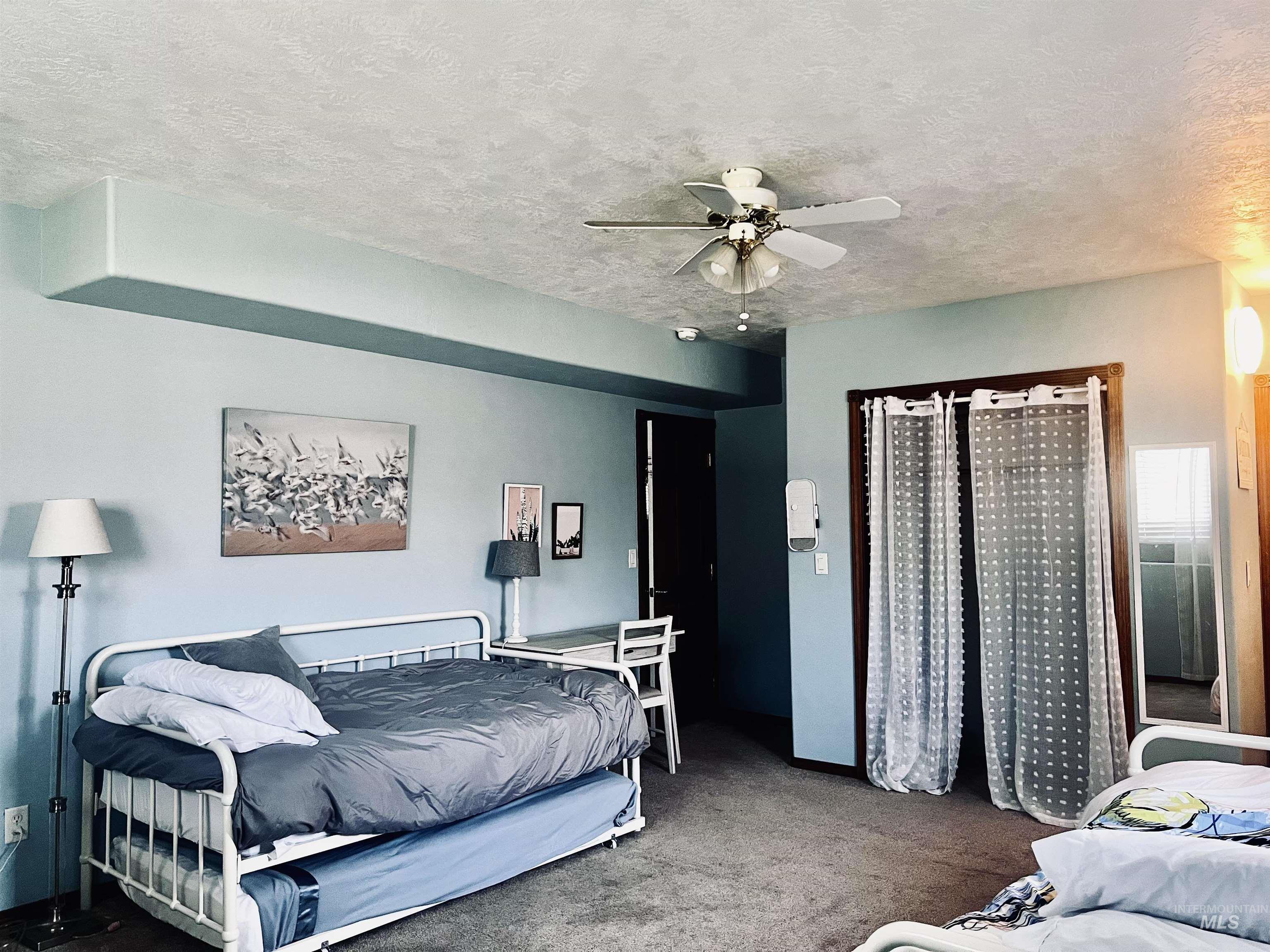 Bedroom featuring a textured ceiling, ceiling fan, and carpet