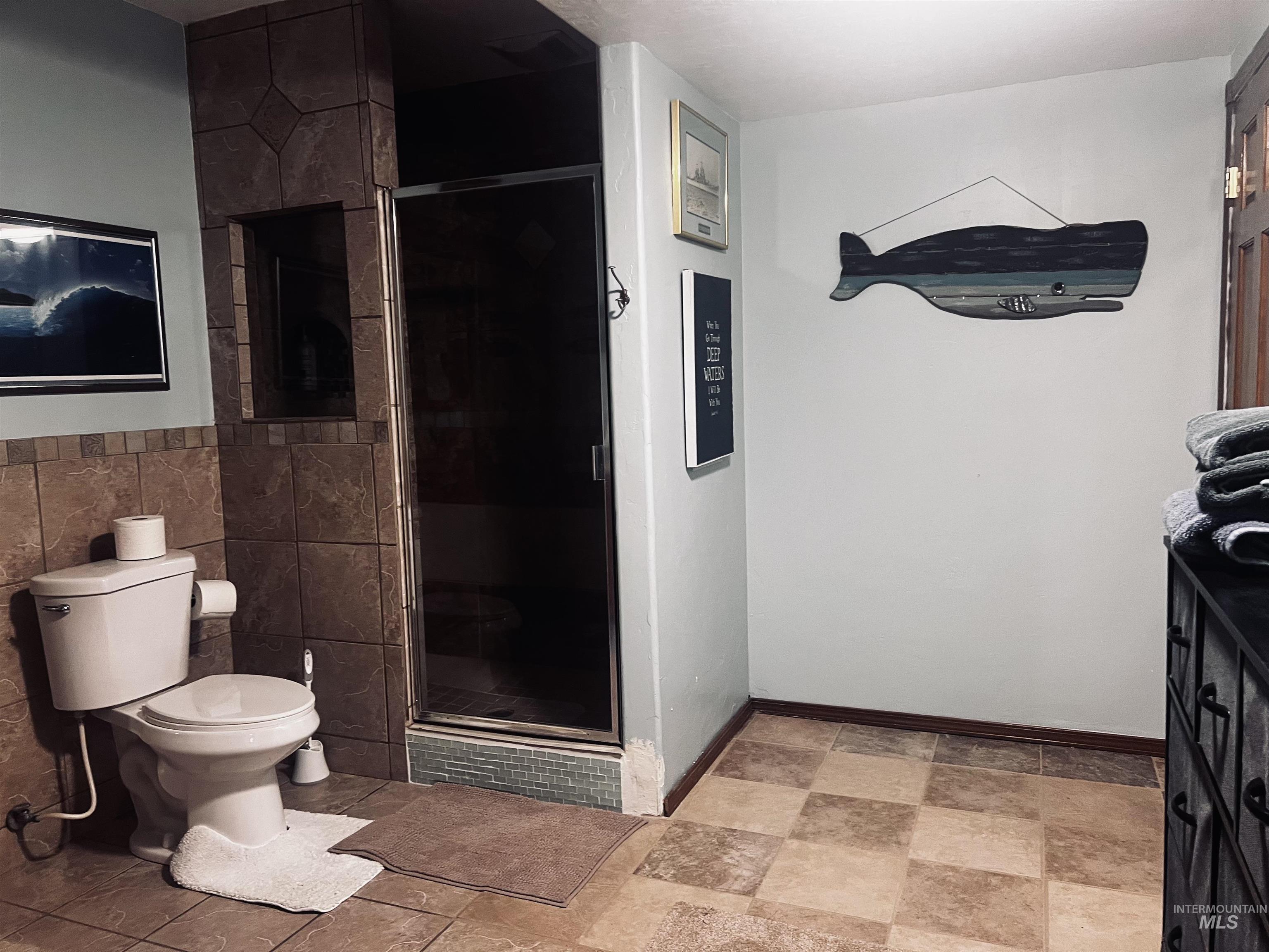 Bathroom featuring tile walls, a shower stall, and vanity