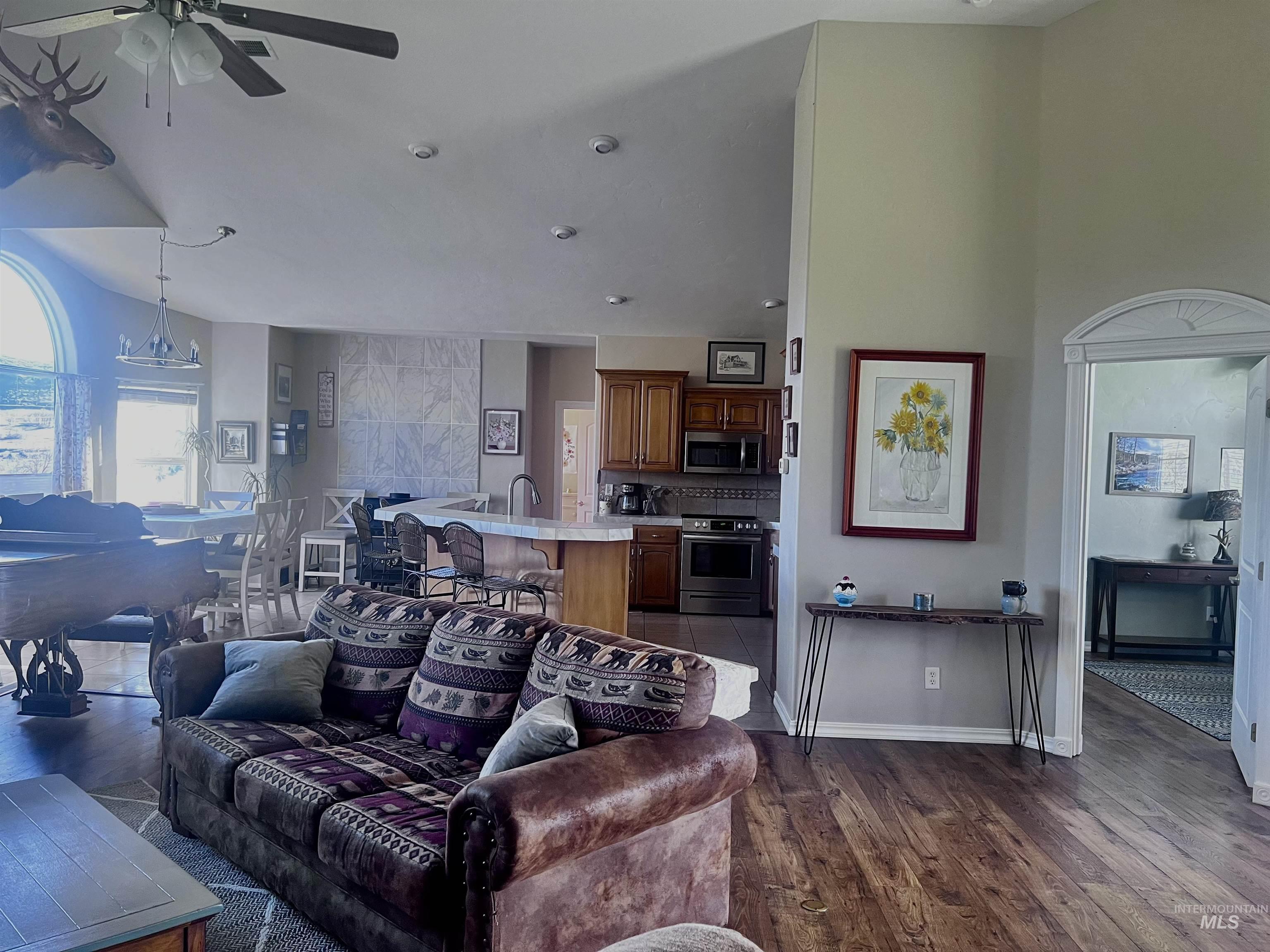 Living area featuring ceiling fan, dark wood finished floors, and lofted ceiling
