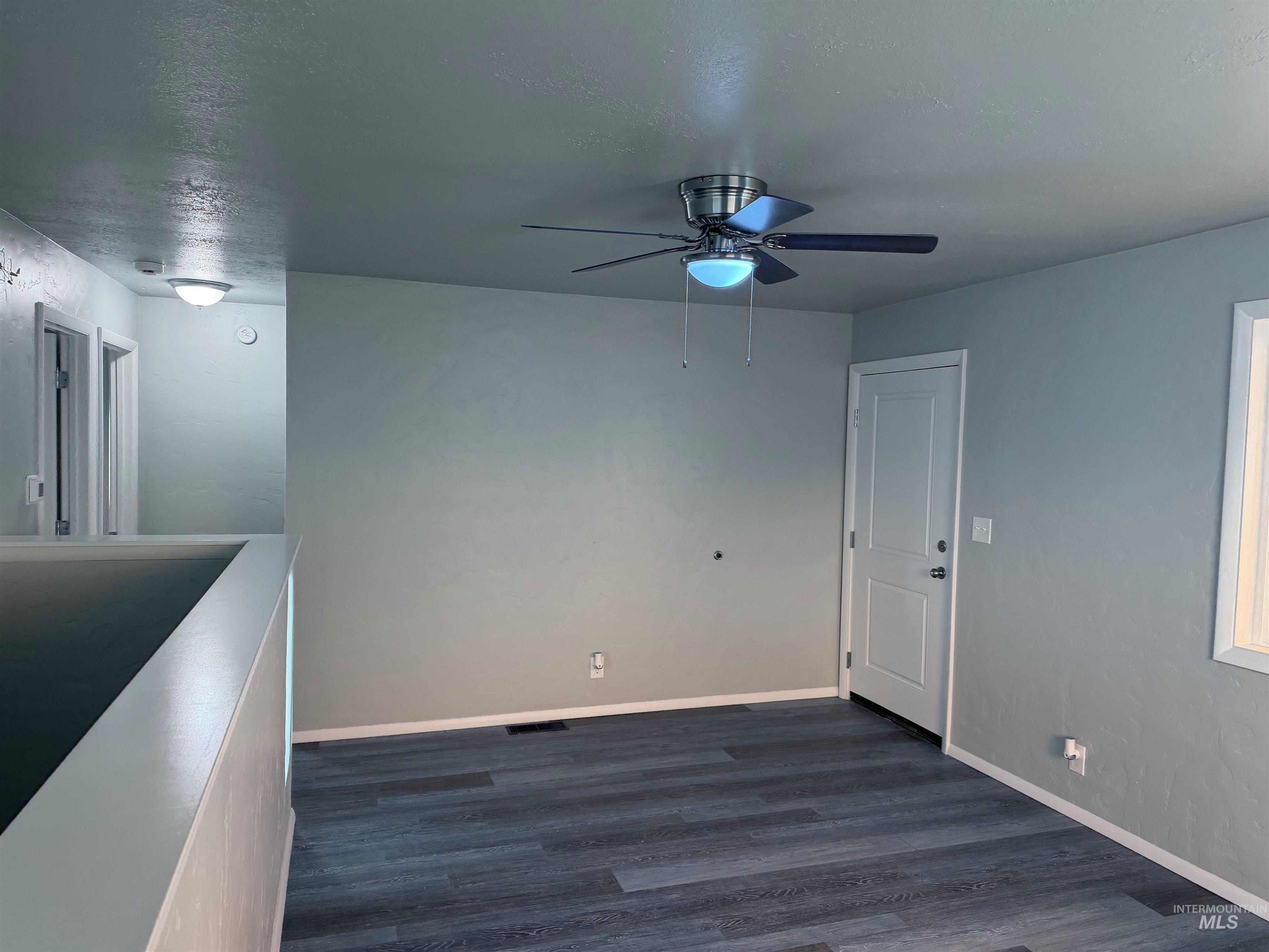 Unfurnished dining area with dark wood finished floors, a textured ceiling, and ceiling fan