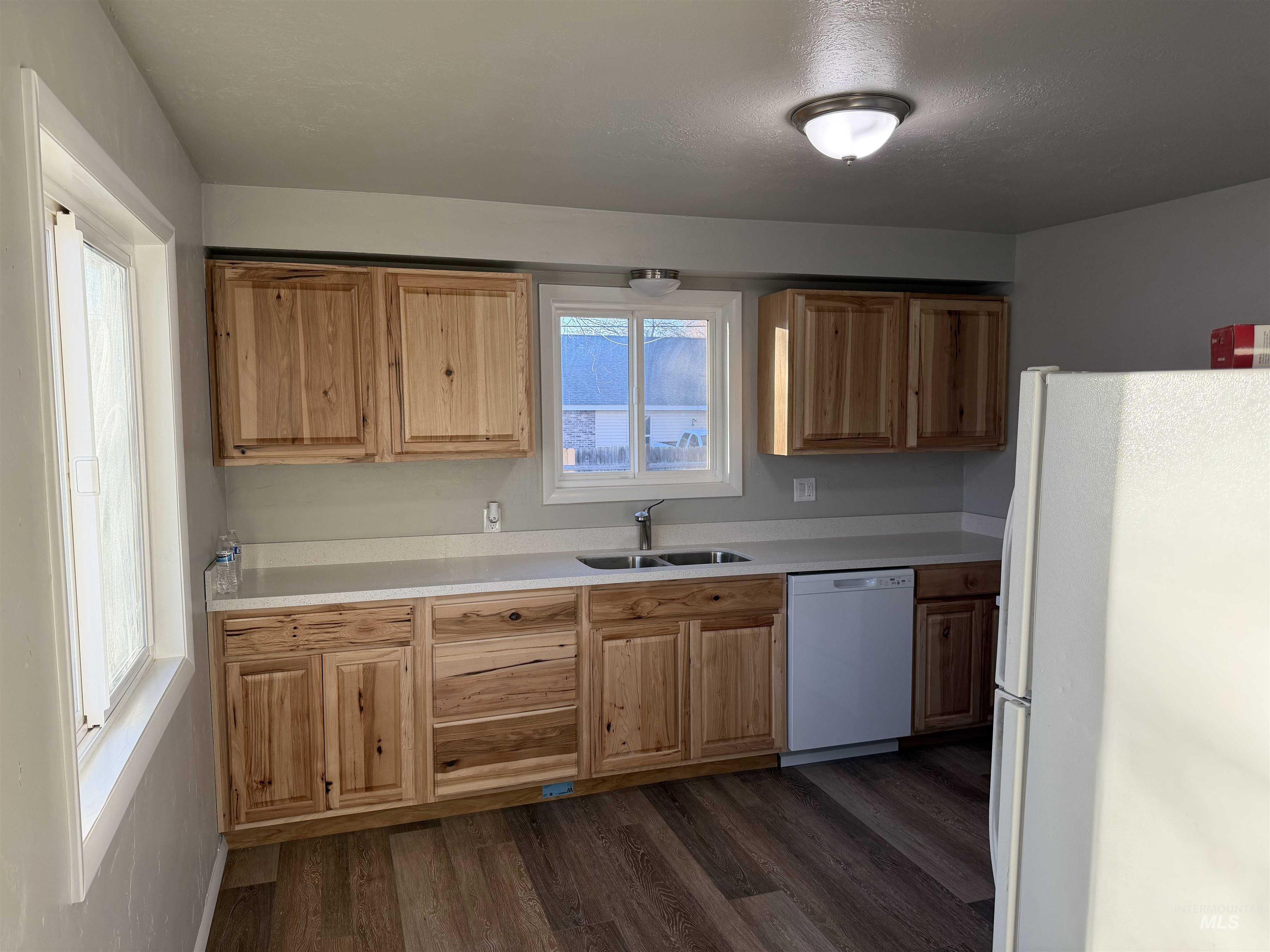 Kitchen featuring light countertops, white appliances, and dark wood-style flooring