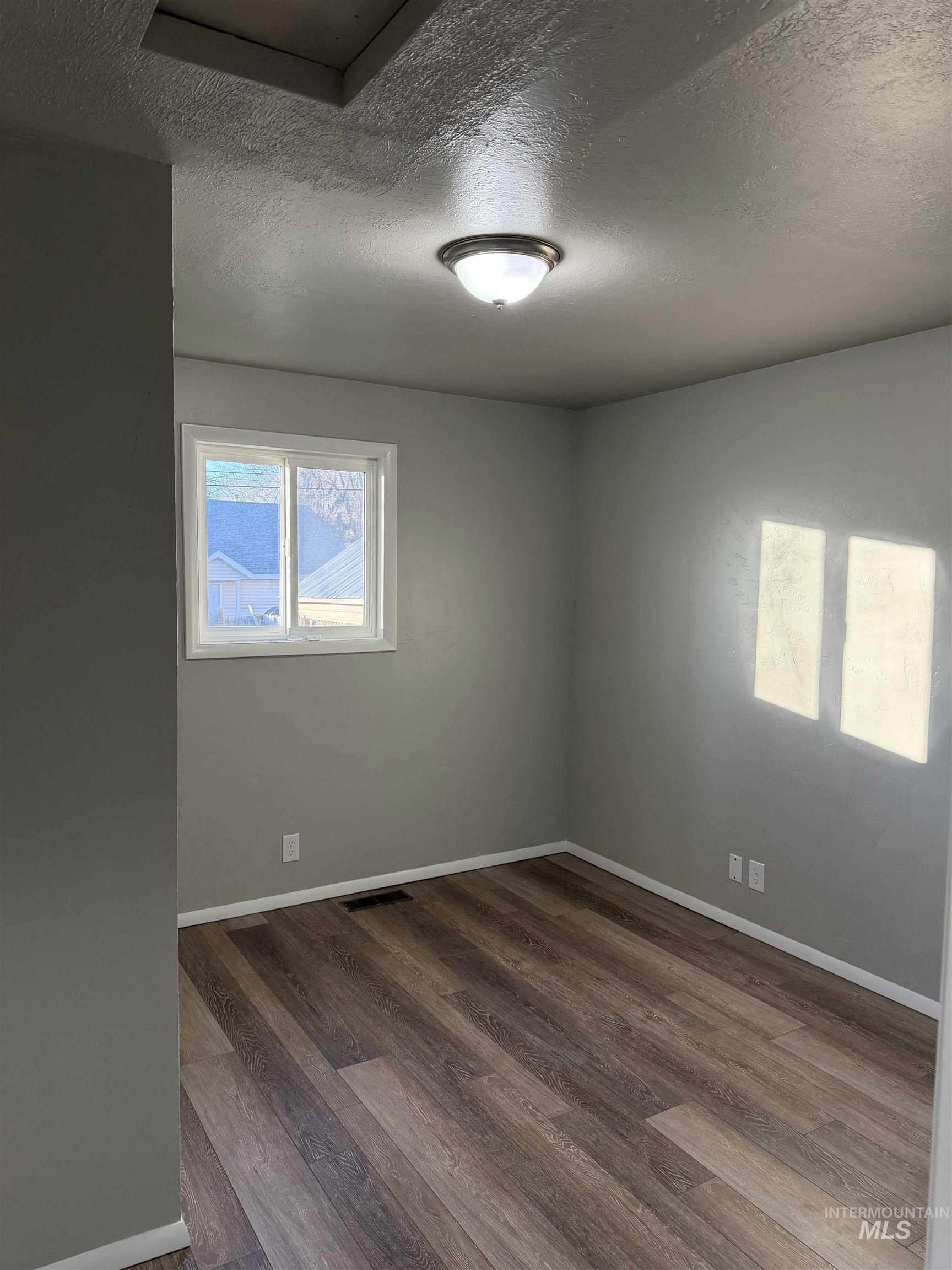 Unfurnished room with a textured ceiling and dark wood-style floors