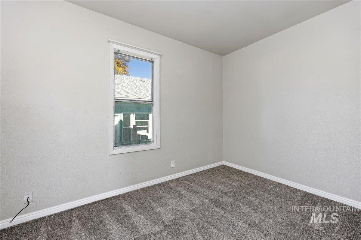 Carpeted spare room featuring baseboards
