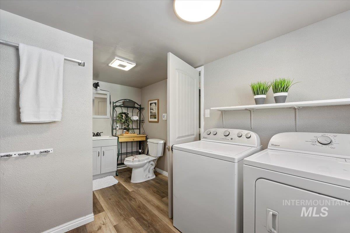 Laundry area with dark wood-type flooring, washing machine and dryer, and a textured wall