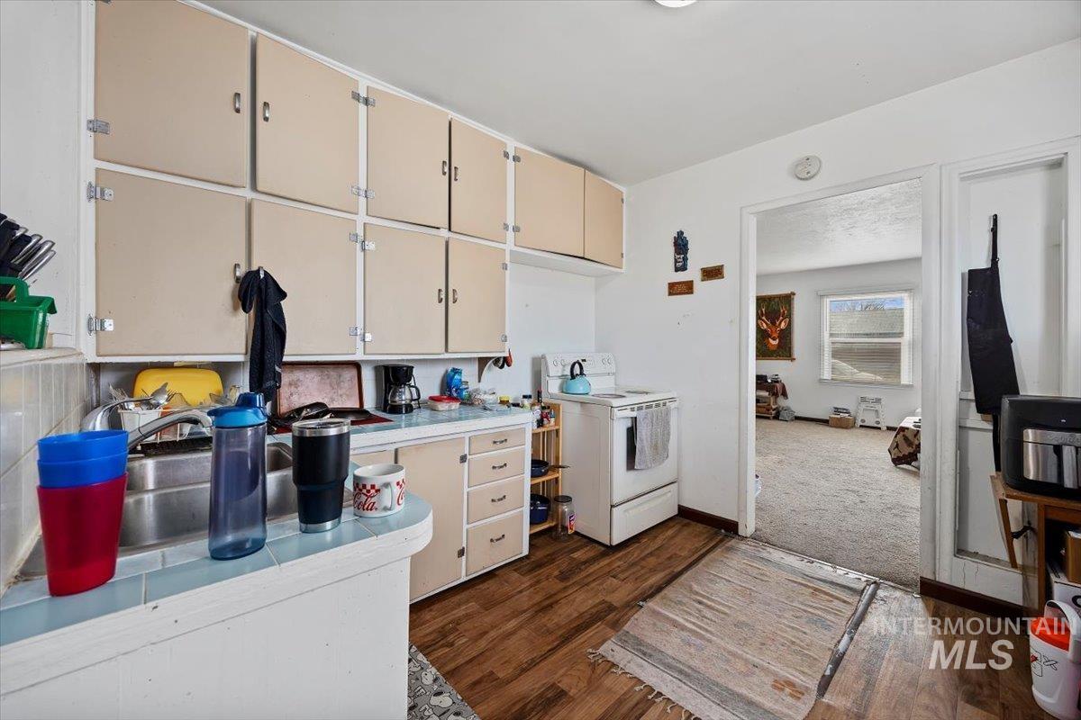 Kitchen with white electric range oven, dark wood-style flooring, and cream cabinets