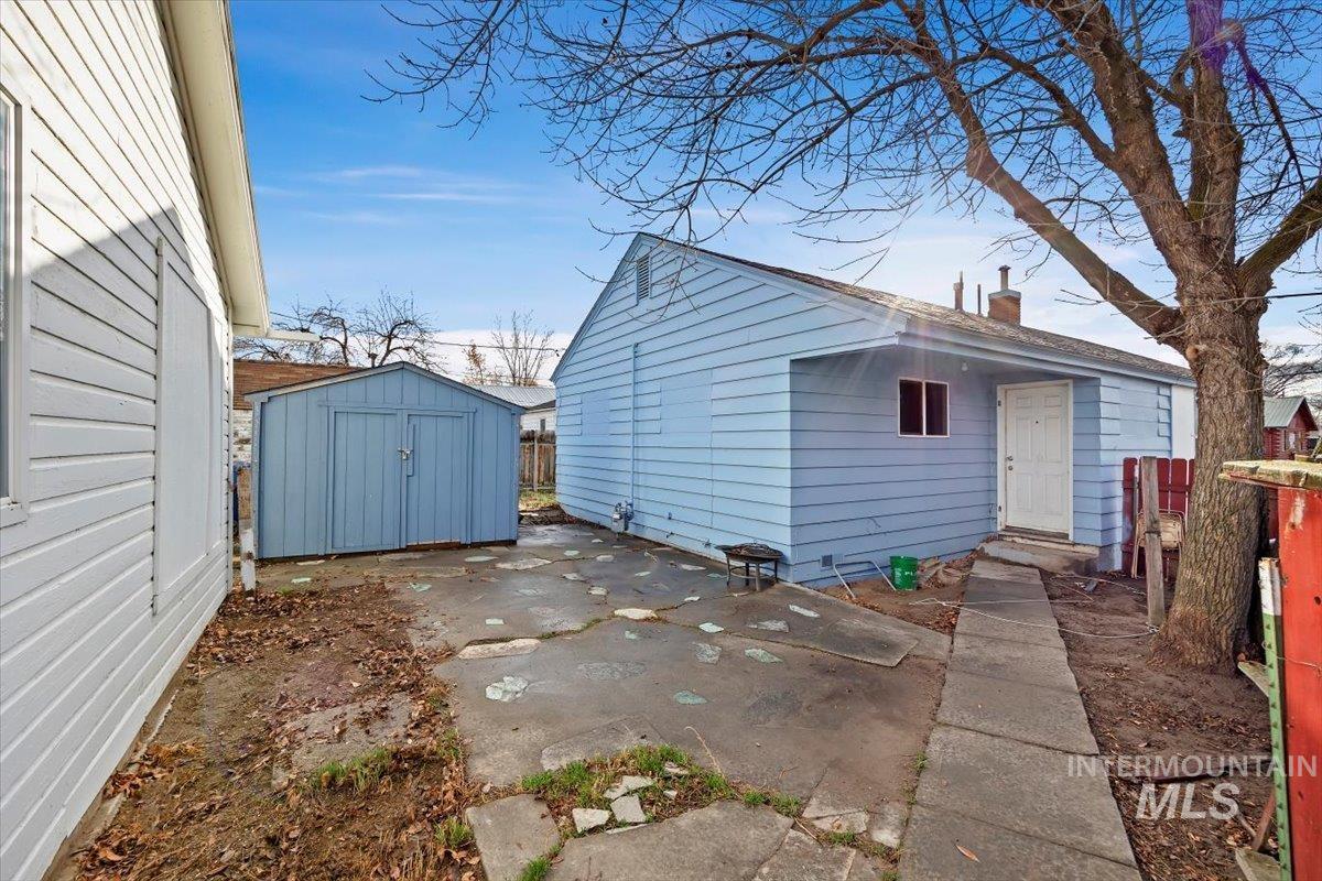 Rear view of house featuring a patio area, a chimney, and a shed