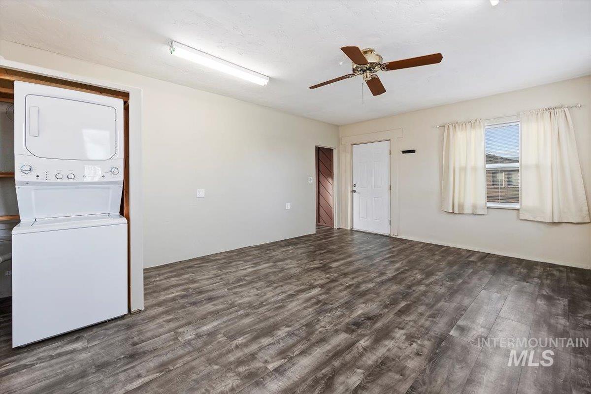 Spare room featuring estacked washer and dryer, dark wood finished floors, and ceiling fan