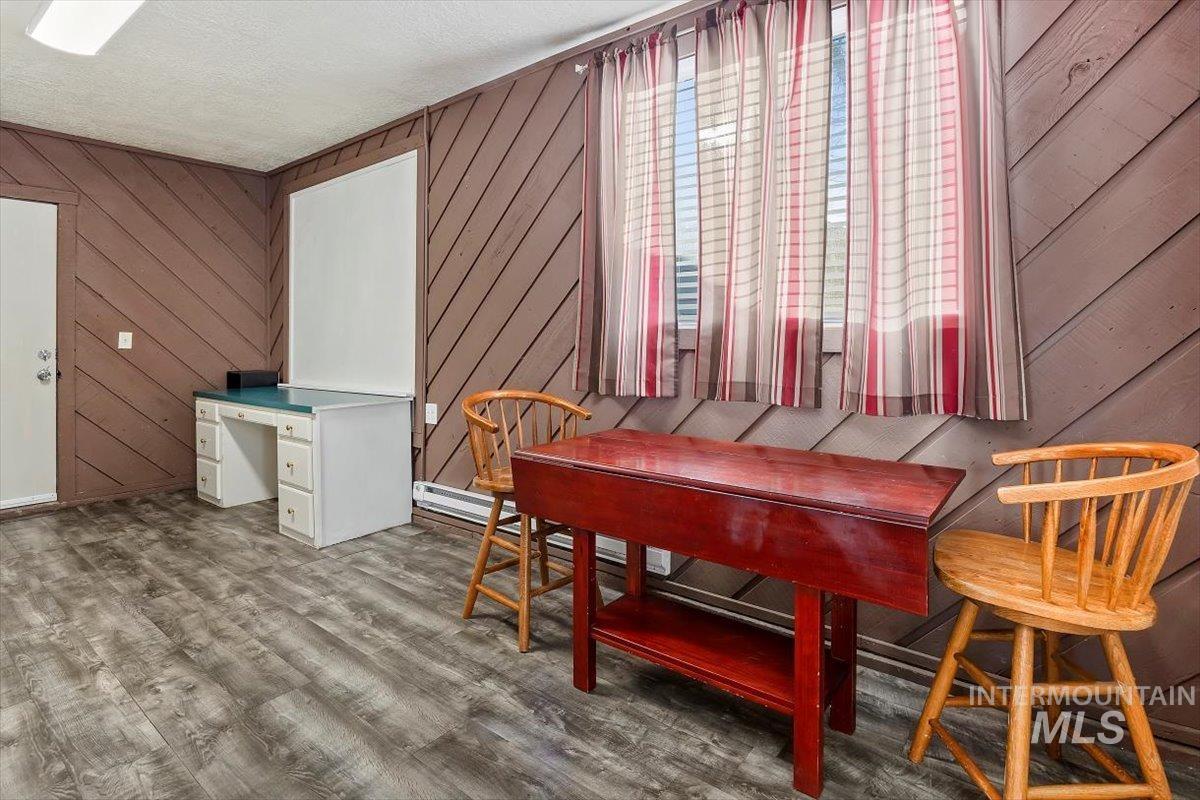Dining room with wood walls, a textured ceiling, a desk, and wood finished floors