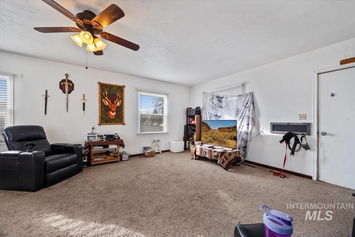 Living area featuring carpet, a ceiling fan, and a textured ceiling