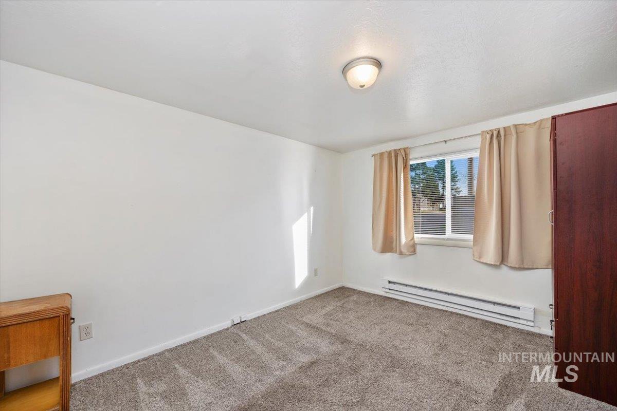 Carpeted empty room with baseboard heating and baseboards