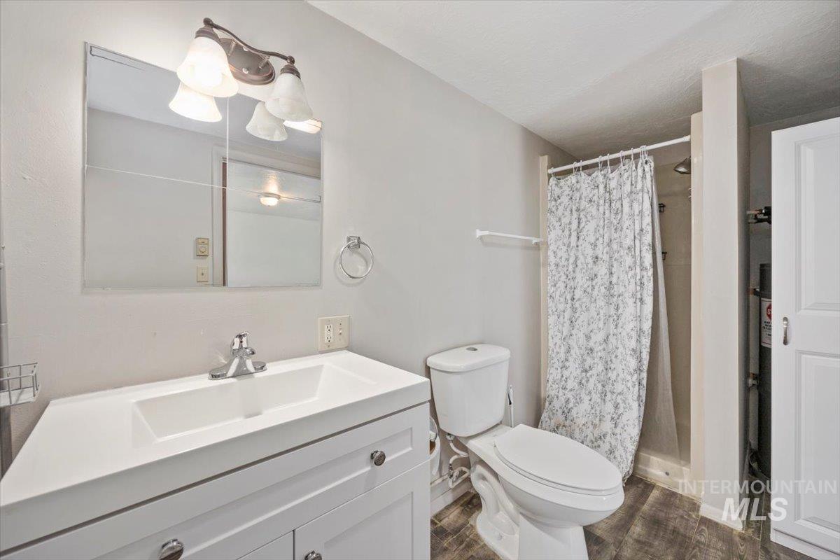 Full bath with a stall shower, vanity, and dark wood finished floors