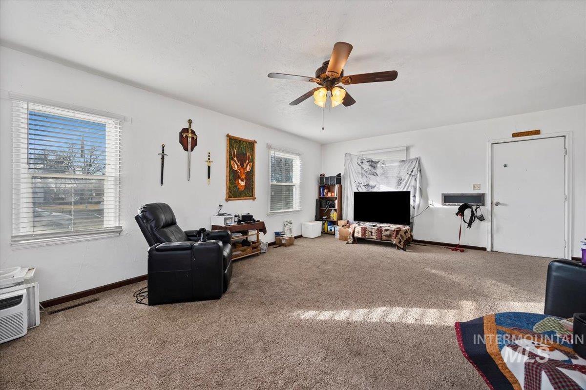 Carpeted living area with healthy amount of natural light and ceiling fan