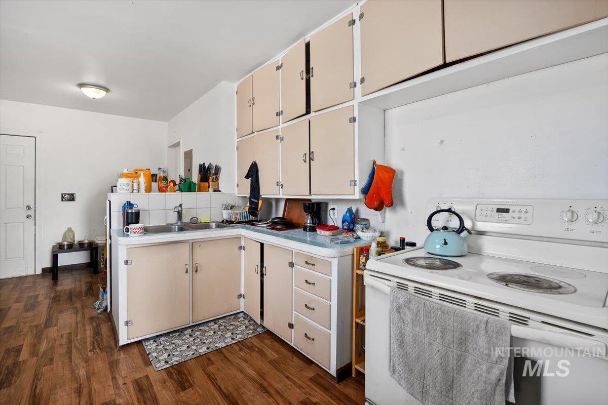 Kitchen with electric range, light countertops, dark wood-style flooring, and cream cabinets