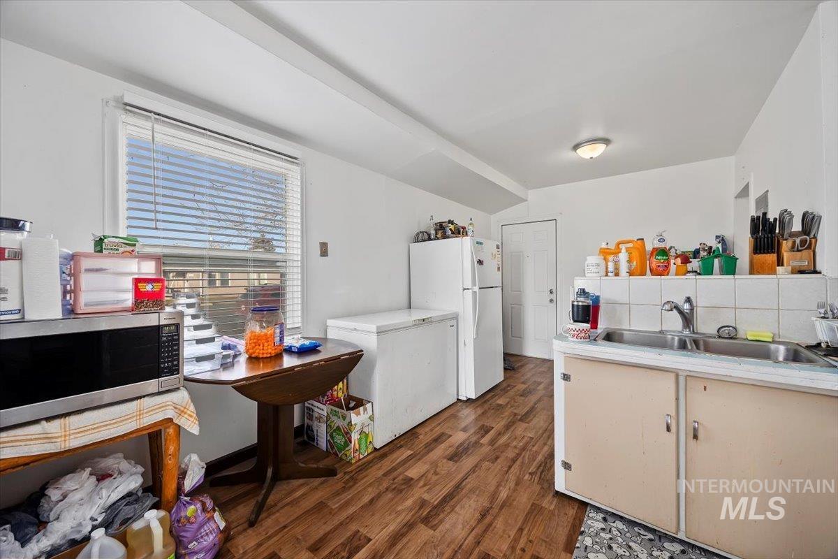 Kitchen with stainless steel microwave, fridge, light countertops, tasteful backsplash, and lofted ceiling