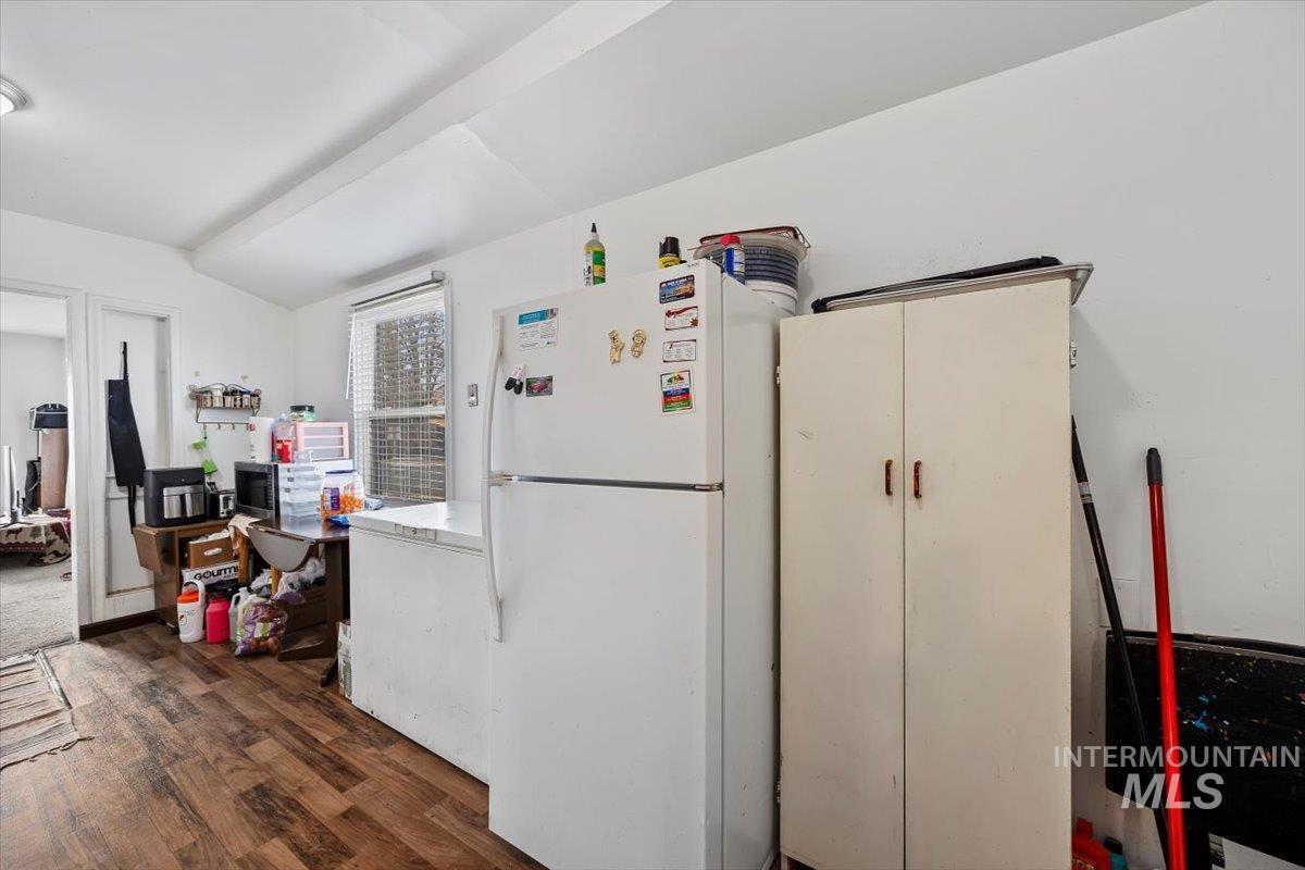Kitchen with freestanding refrigerator, white fridge, dark wood finished floors, vaulted ceiling, and stainless steel microwave