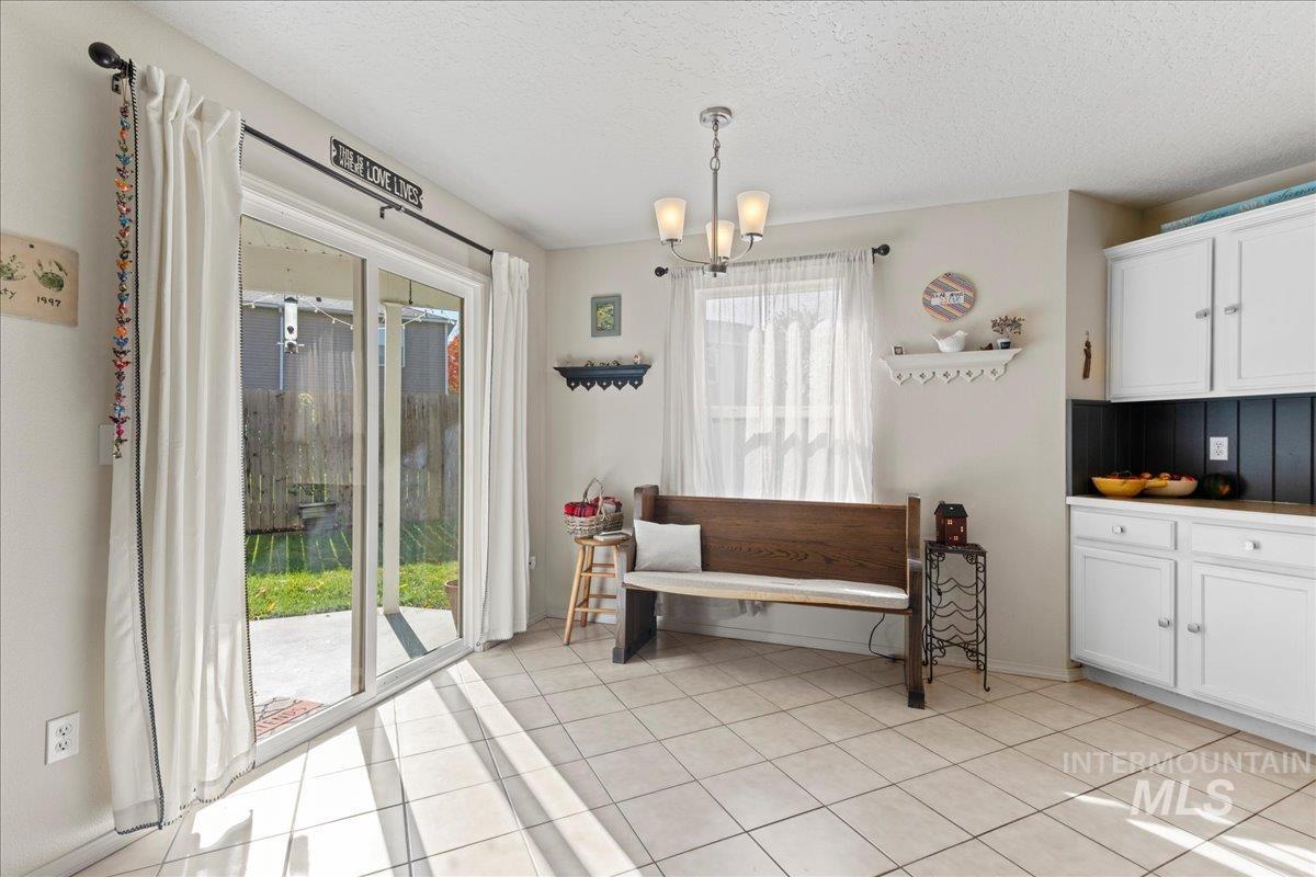 Sitting room with a textured ceiling, light tile patterned flooring, and a chandelier
