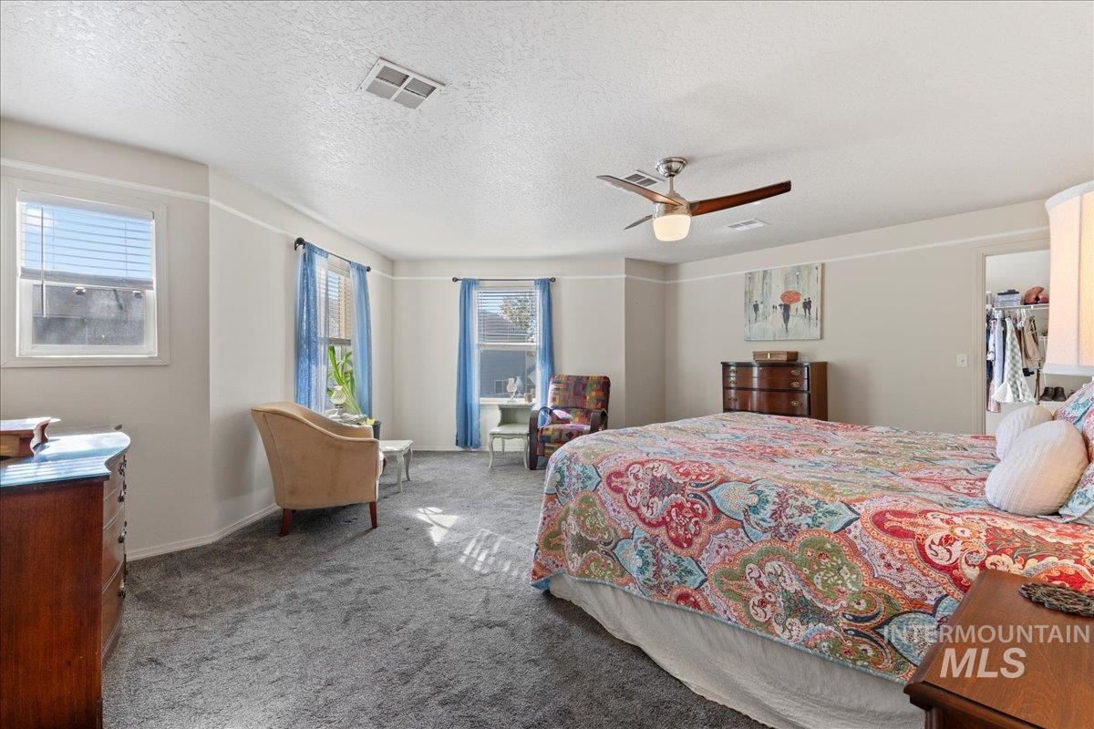 Bedroom with a textured ceiling, carpet floors, a ceiling fan, and a spacious closet