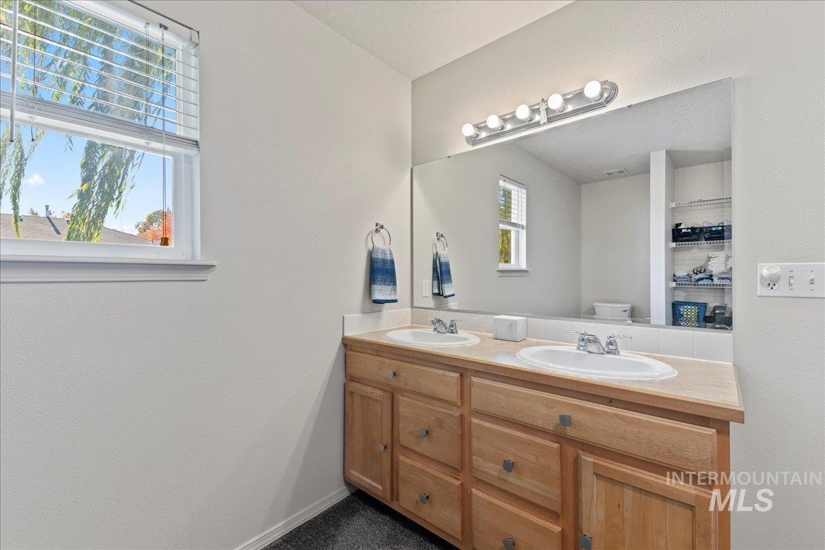 Full bath with double vanity and a textured wall