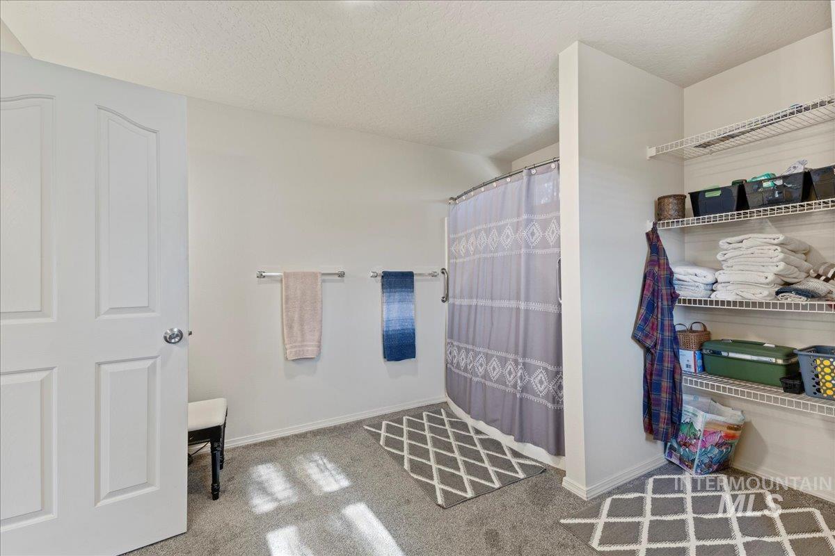 Full bathroom with a shower with curtain, a textured ceiling, and carpet floors