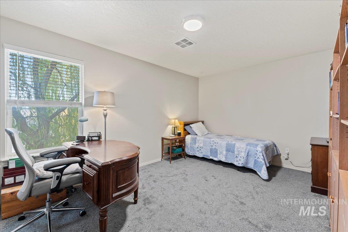 Bedroom featuring light carpet, a desk, and a textured ceiling