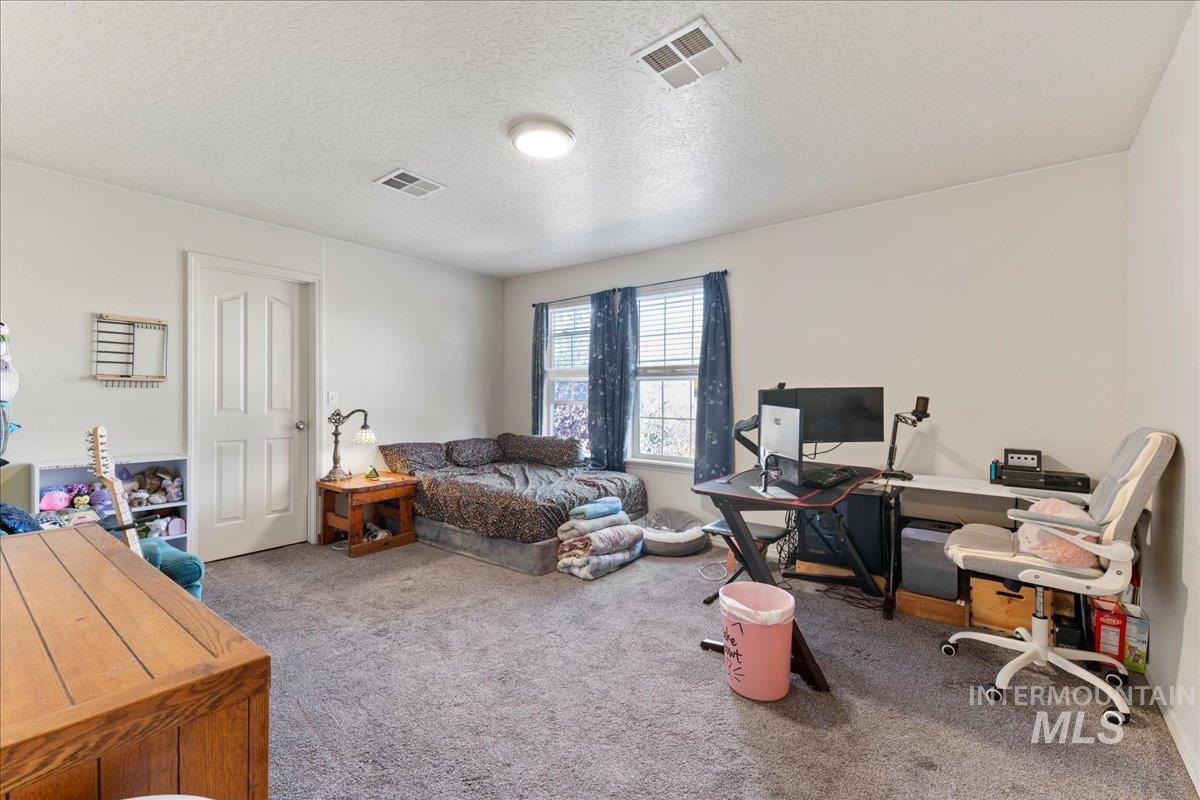 Home office with light colored carpet and a textured ceiling