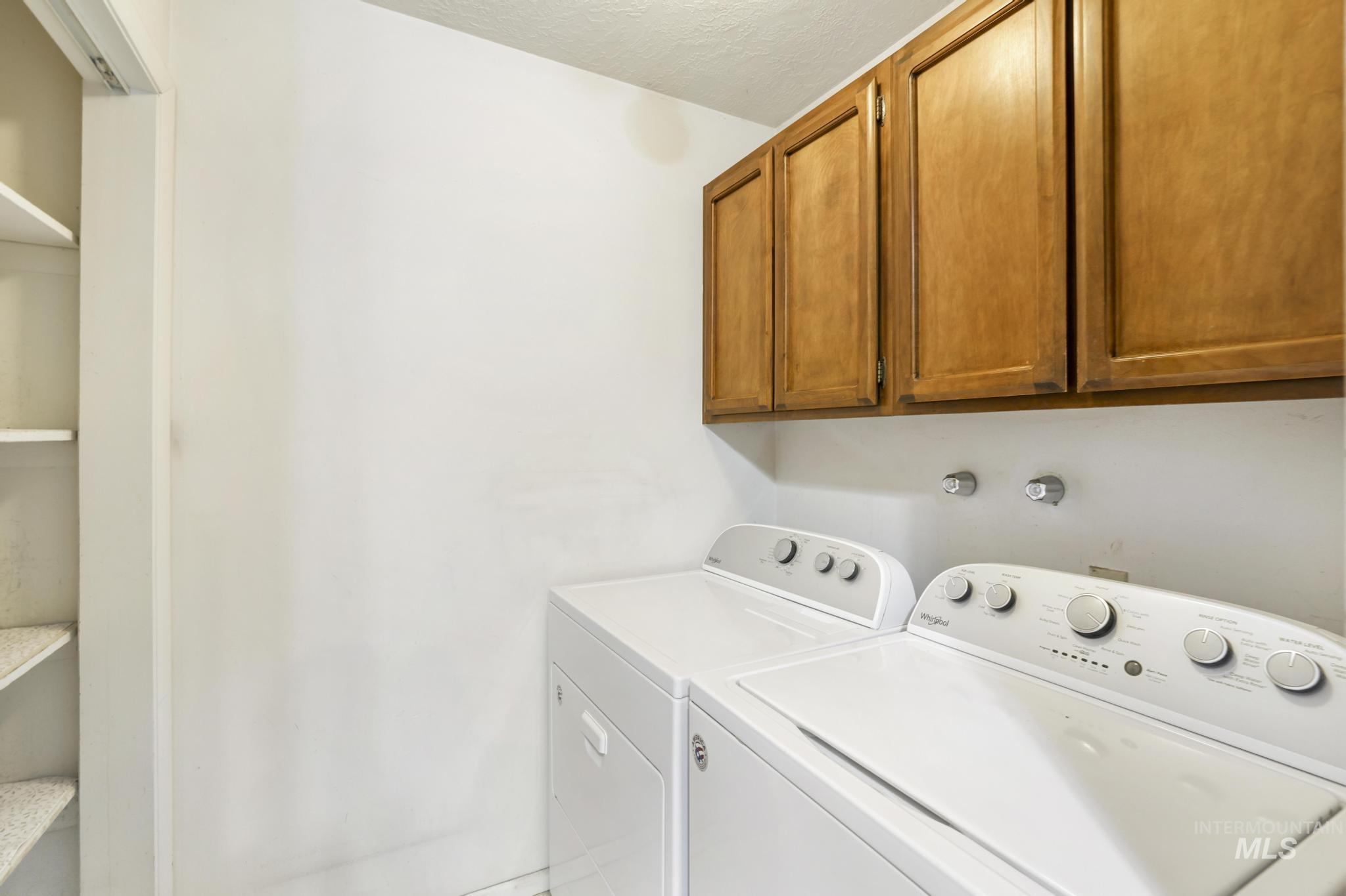 Washroom with washer and clothes dryer and cabinet space