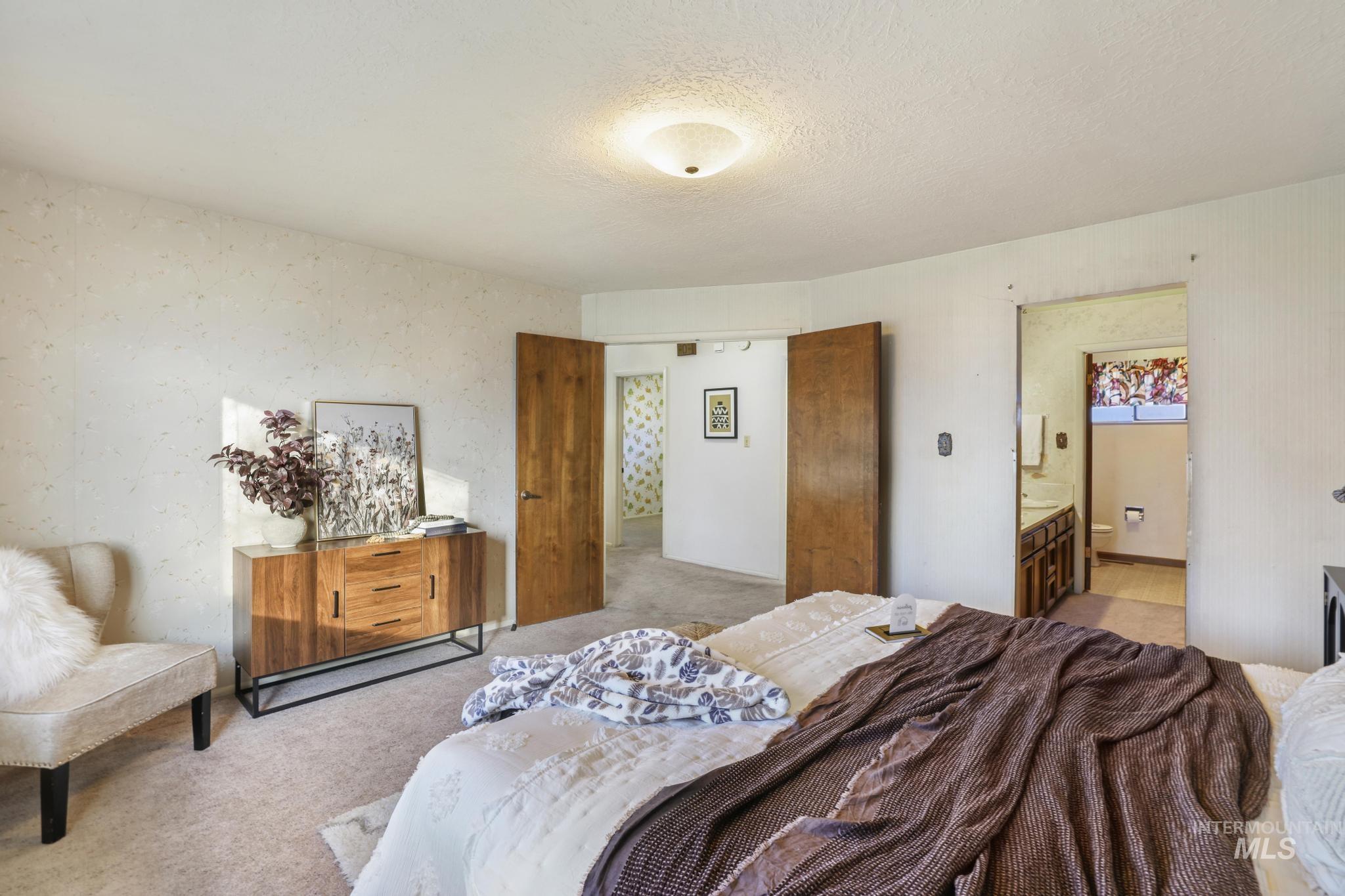Bedroom featuring wallpapered walls, connected bathroom, a textured ceiling, and carpet floors