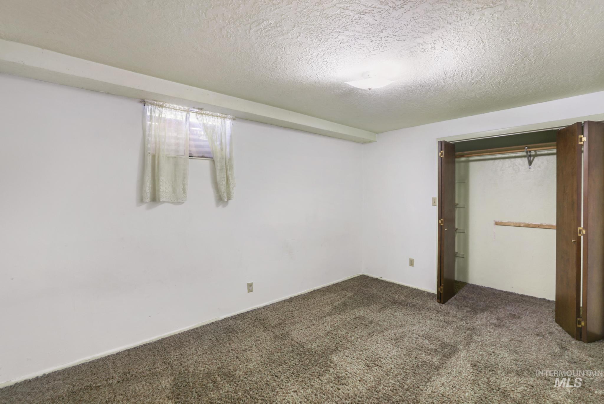 Unfurnished bedroom featuring a textured ceiling, a closet, and dark carpet