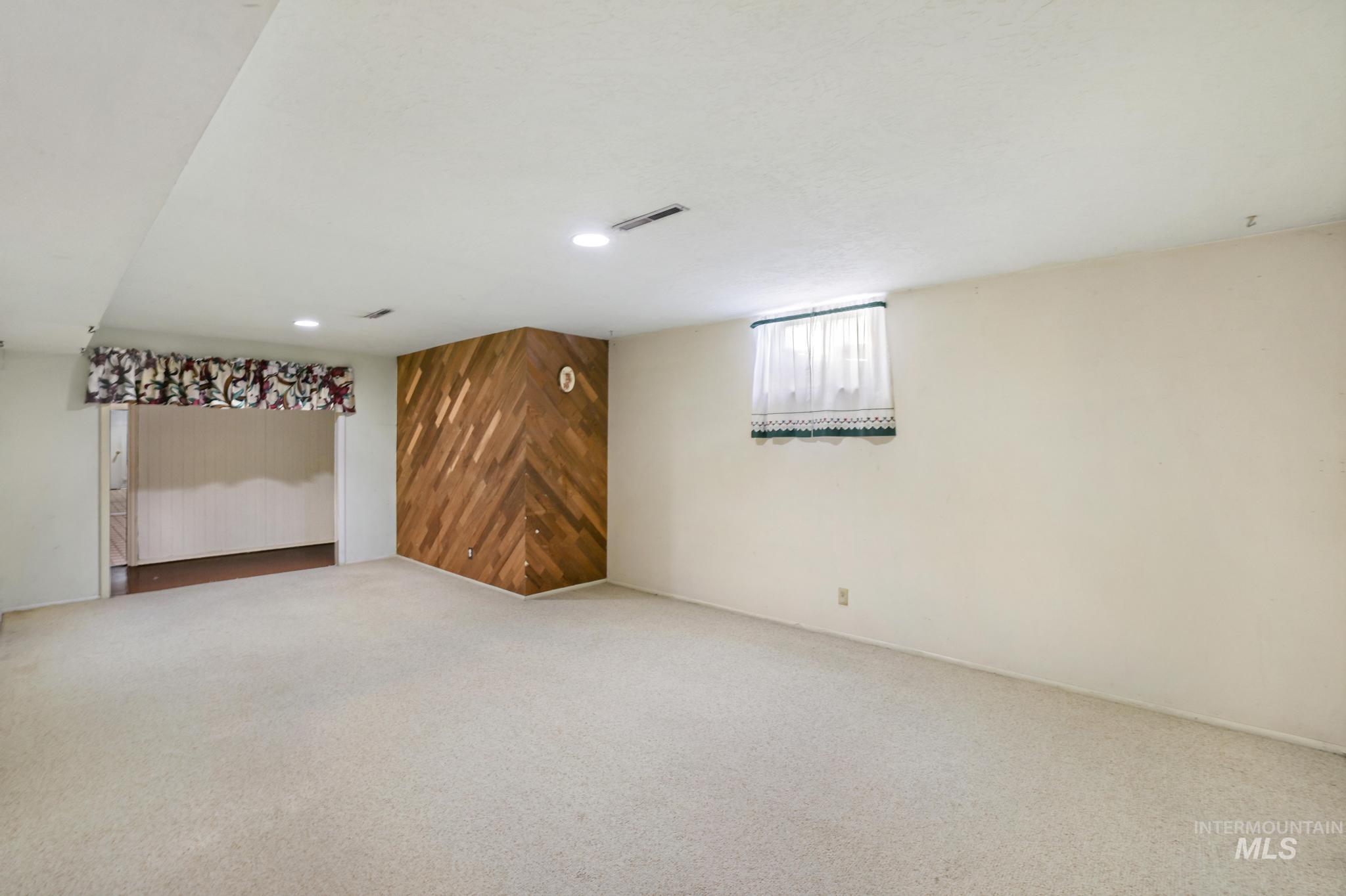 Below grade area featuring wooden walls, an accent wall, carpet floors, and recessed lighting