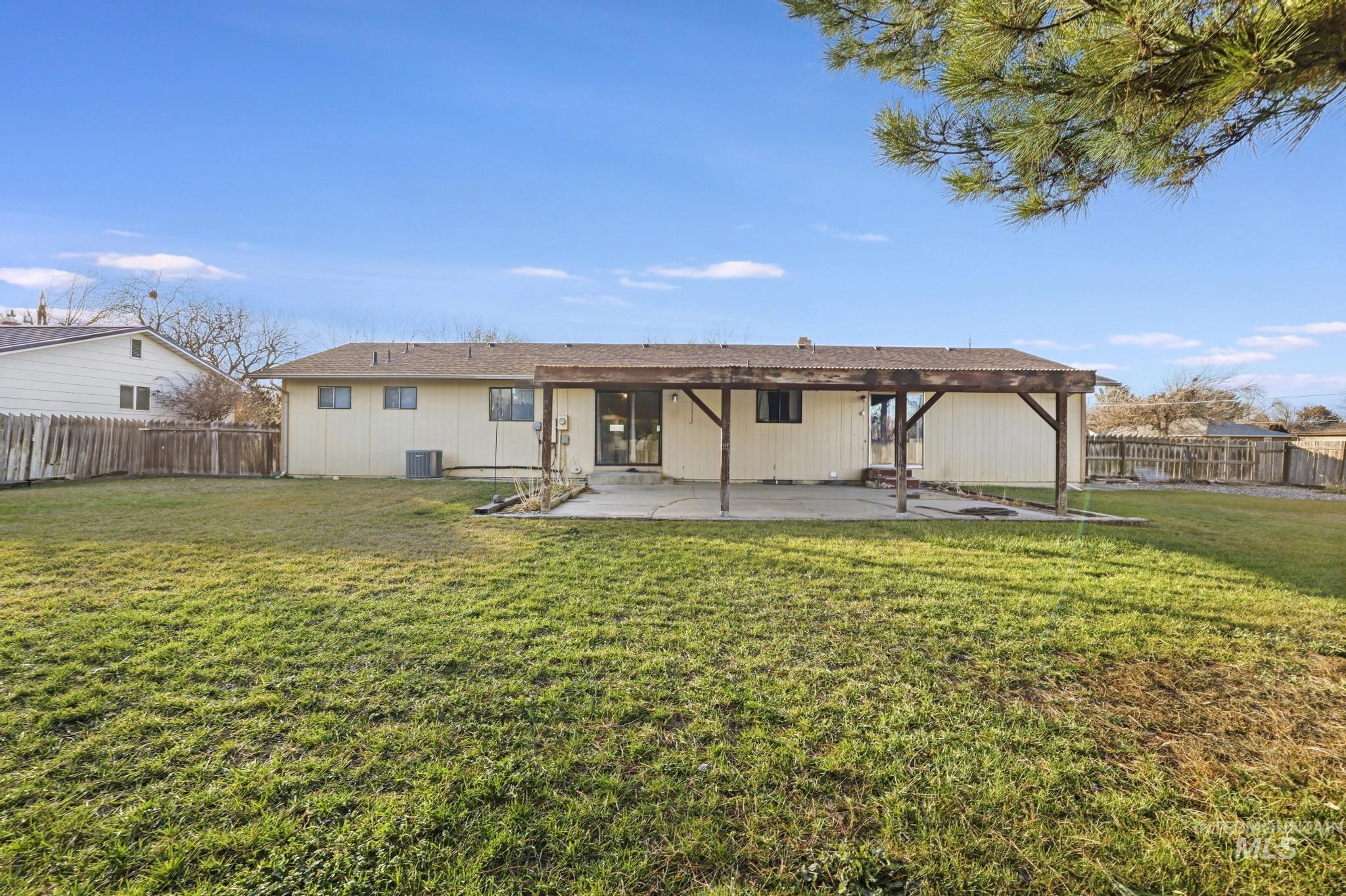 Rear view of house with a fenced backyard and a patio area