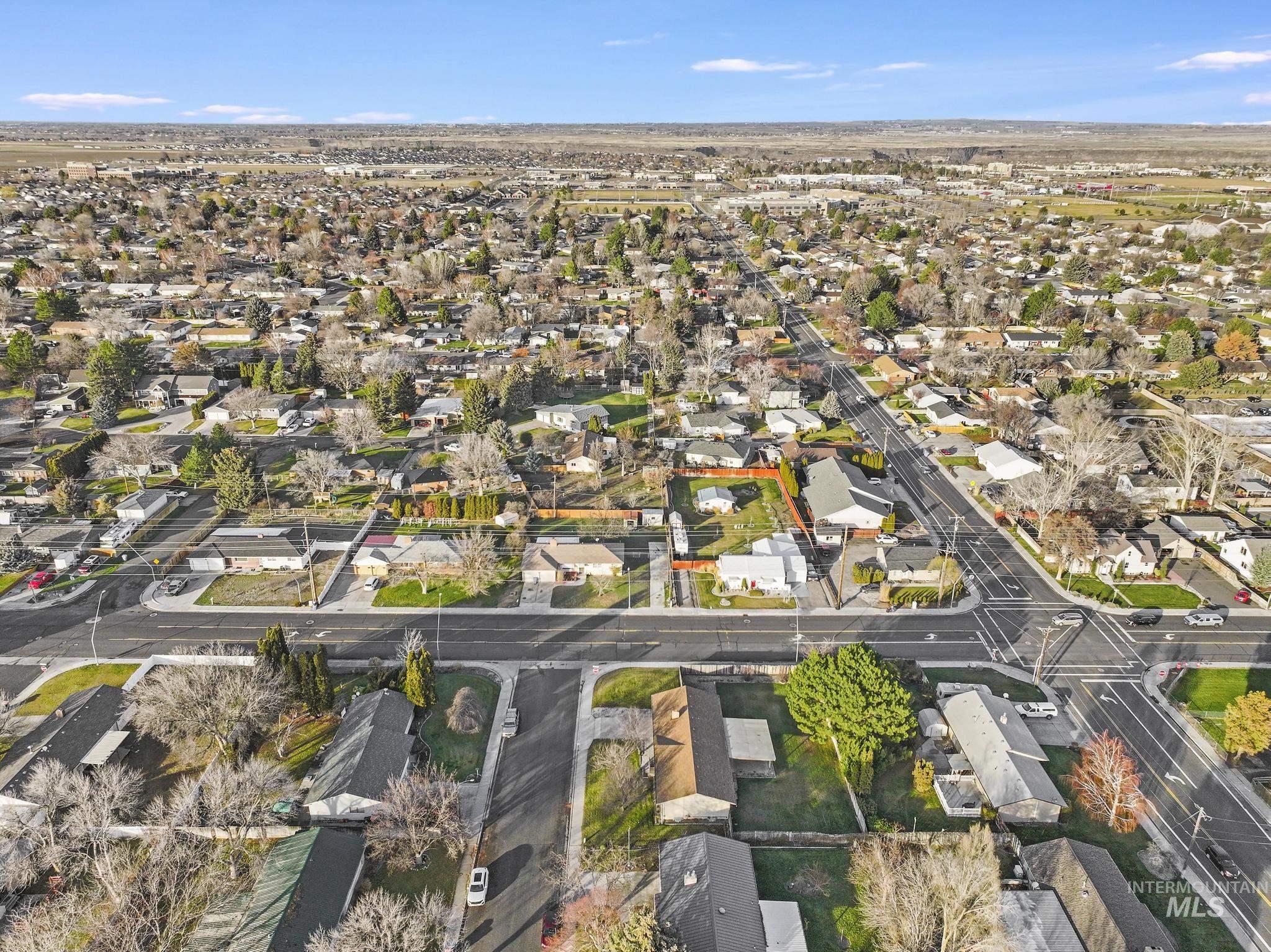Aerial view of property and surrounding area featuring nearby suburban area