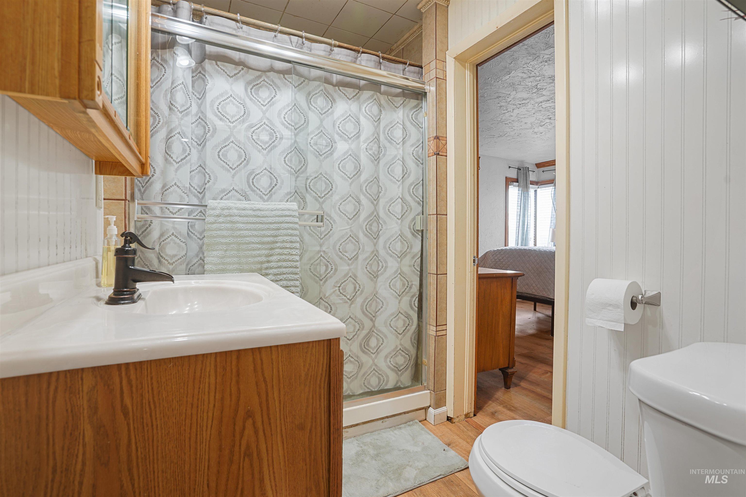 Ensuite bathroom with a shower stall, vanity, and light wood-style flooring