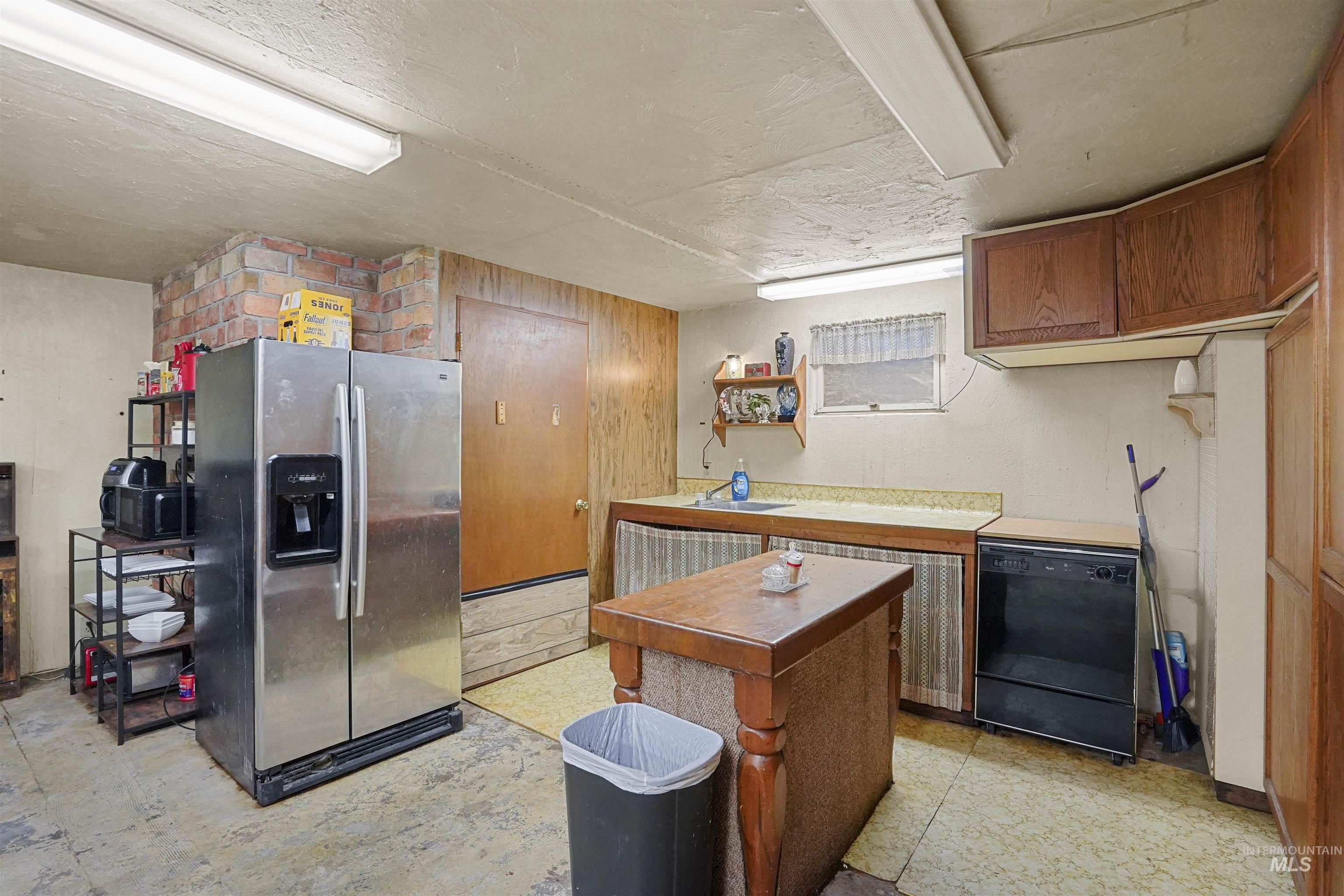 Kitchen featuring stainless steel fridge with ice dispenser, black dishwasher, light countertops, brown cabinets, and light flooring