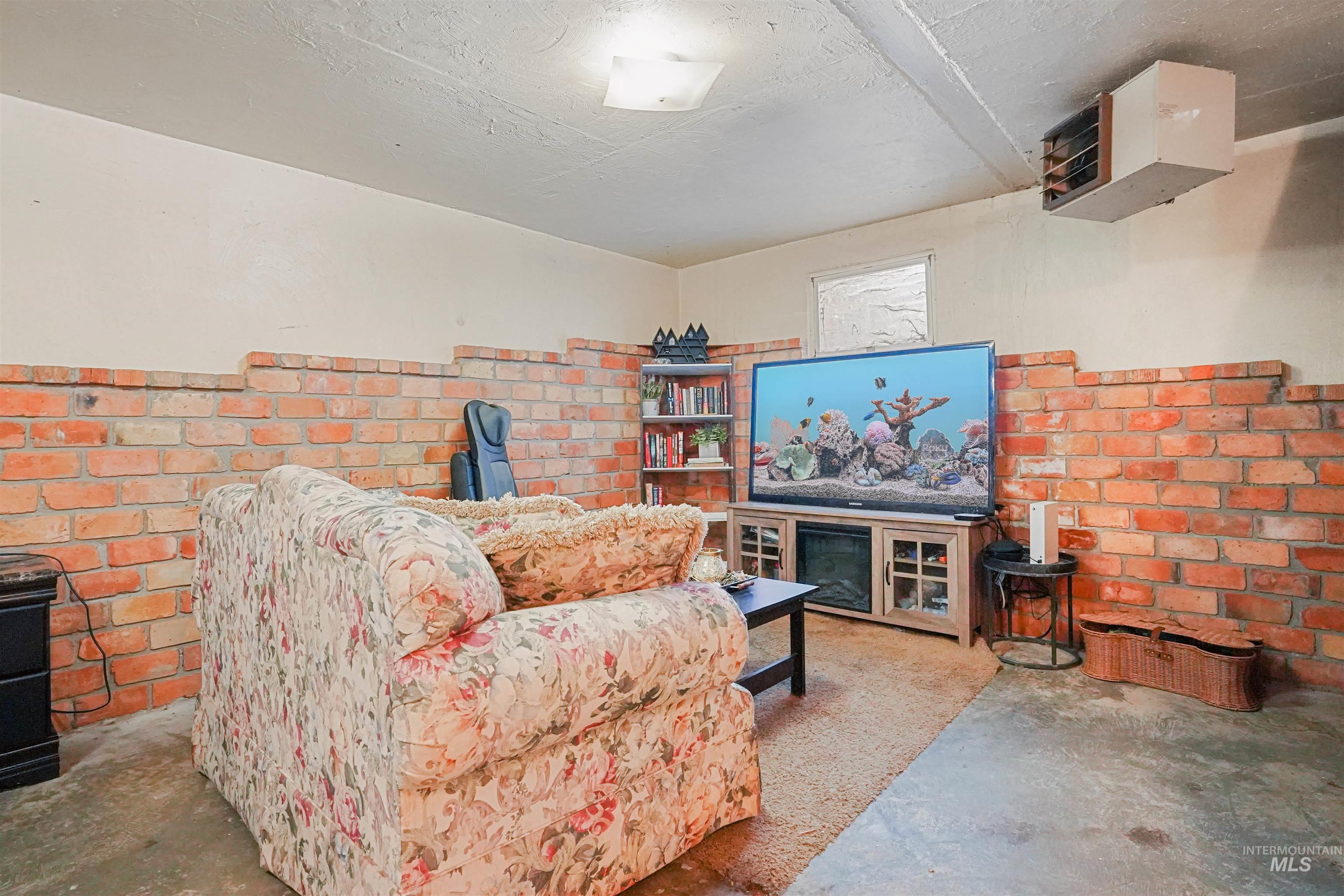 Living room with a heating unit, unfinished concrete flooring, and a textured ceiling