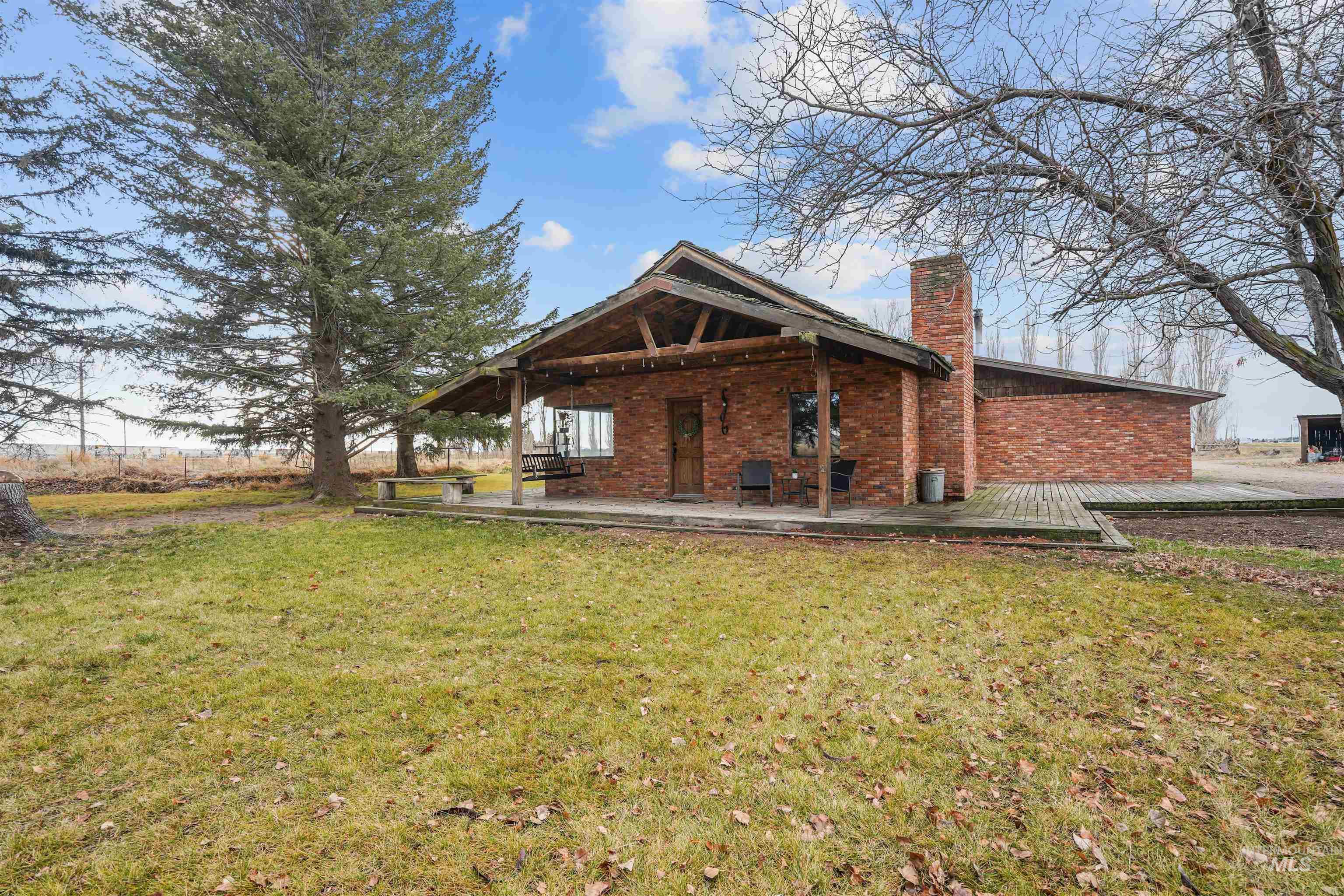 Back of property featuring a lawn, a chimney, and brick siding