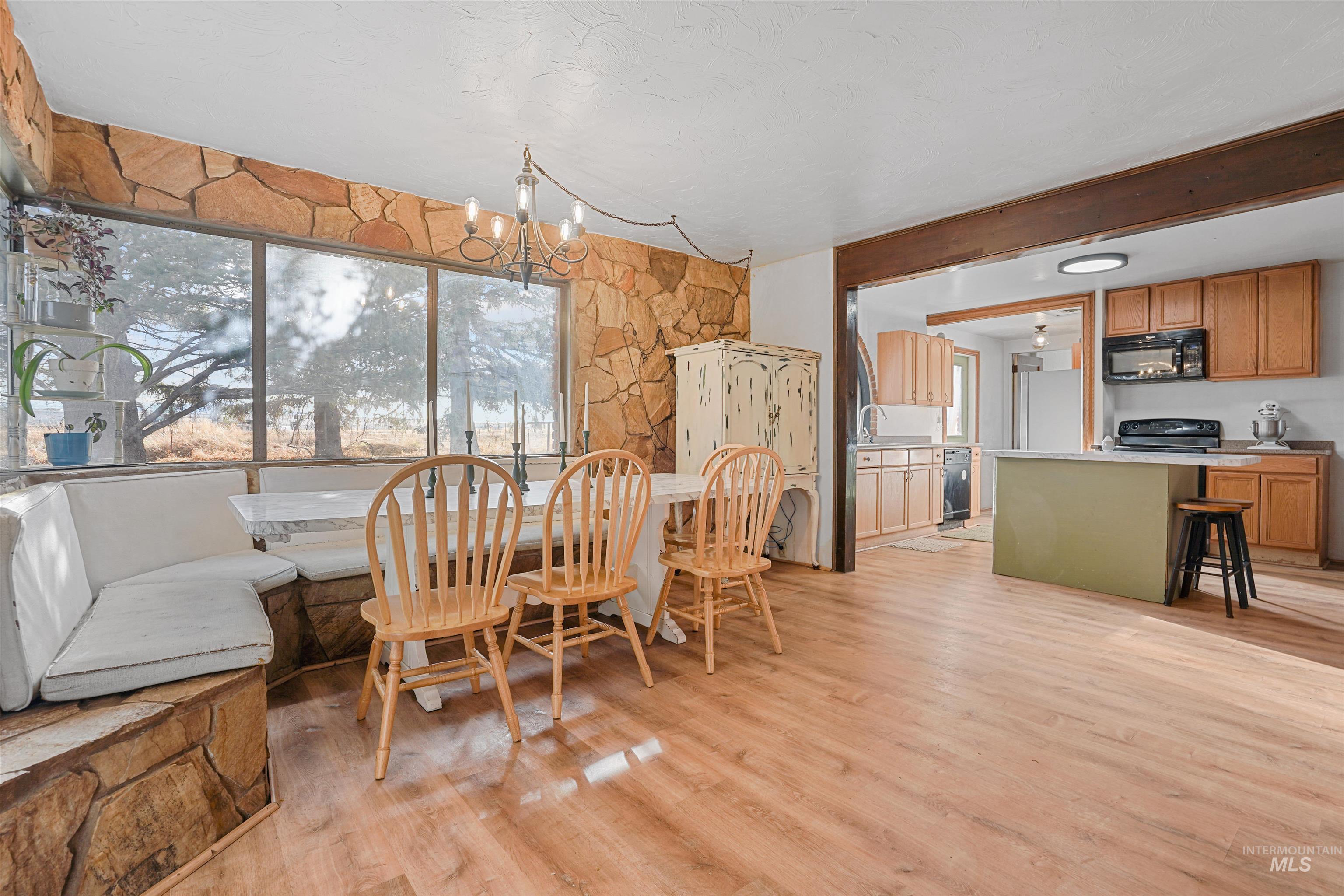Dining area featuring plenty of natural light, a chandelier, light wood finished floors, and beam ceiling