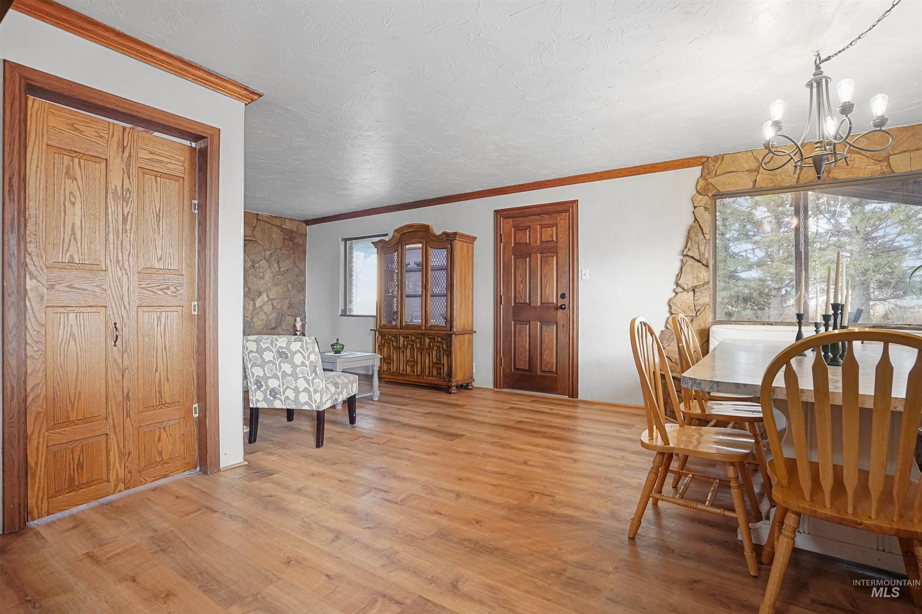 Dining space with ornamental molding, light wood-style floors, a chandelier, and a textured ceiling