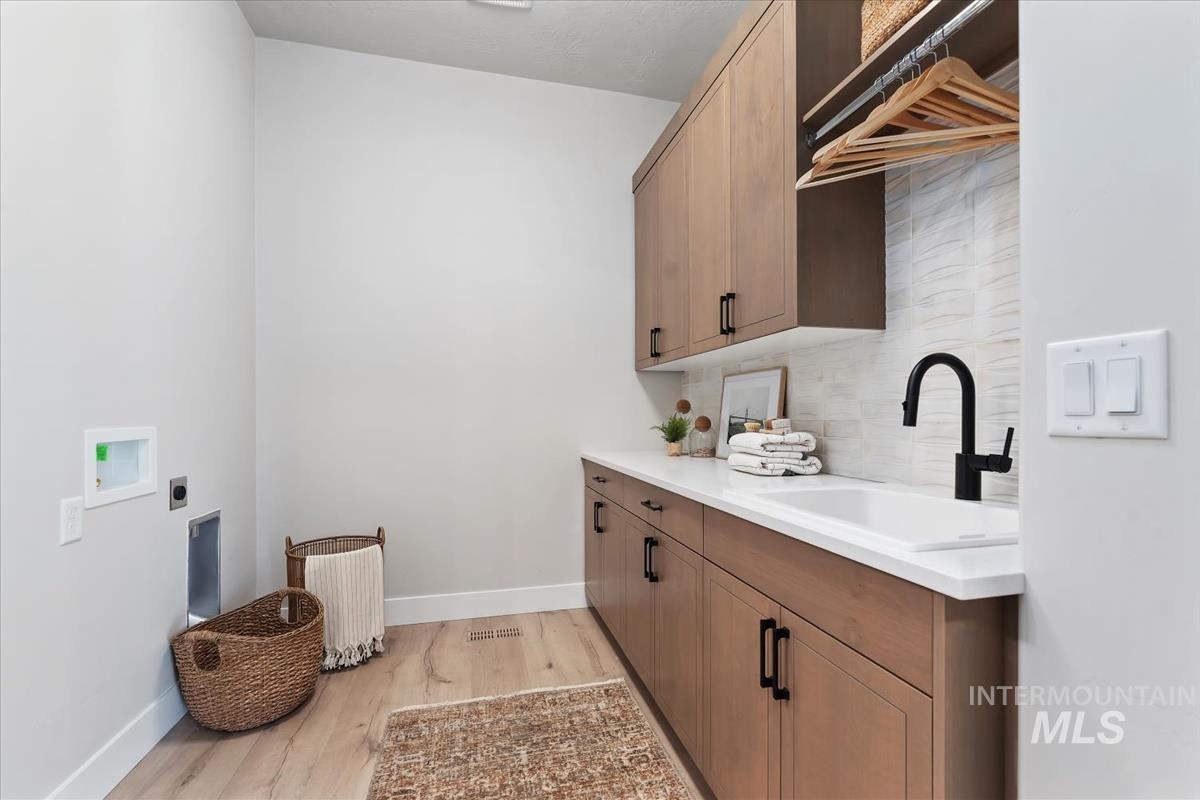 Laundry area featuring hookup for an electric dryer, light wood-style floors, hookup for a washing machine, and cabinet space