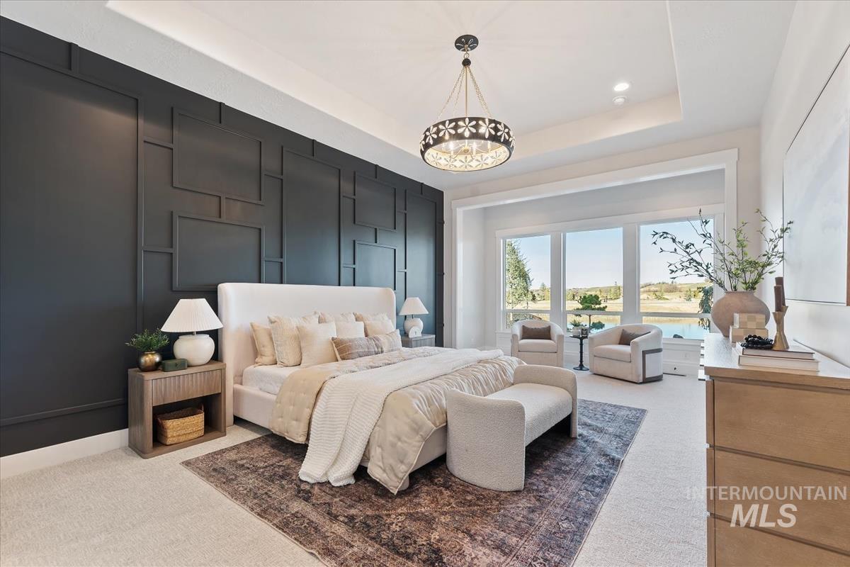 Carpeted bedroom with a tray ceiling and a decorative wall