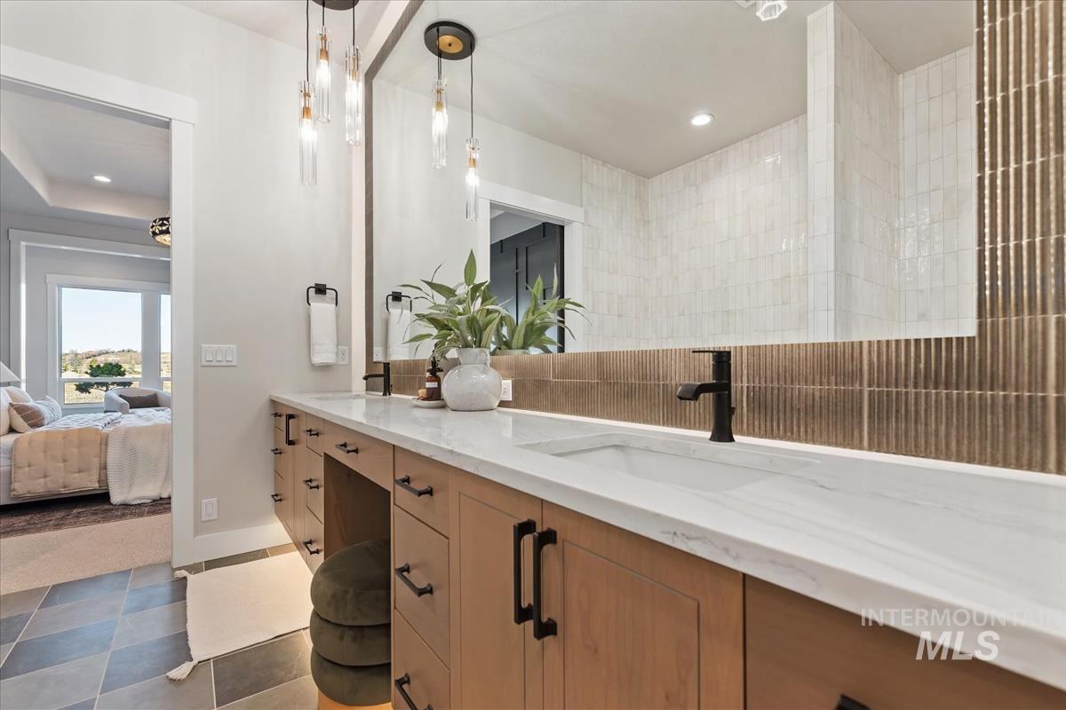Ensuite bathroom featuring double vanity, tasteful backsplash, recessed lighting, and dark tile patterned flooring
