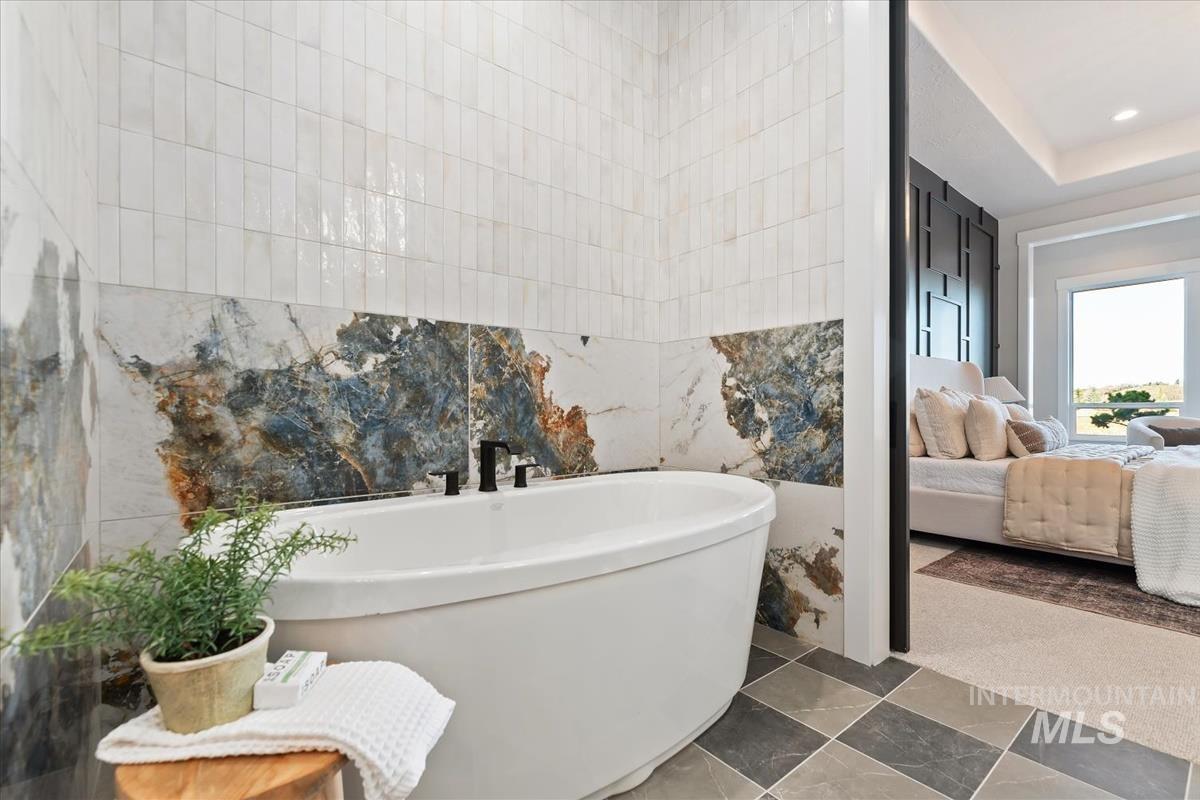 Ensuite bathroom featuring a soaking tub, tile walls, and carpet flooring