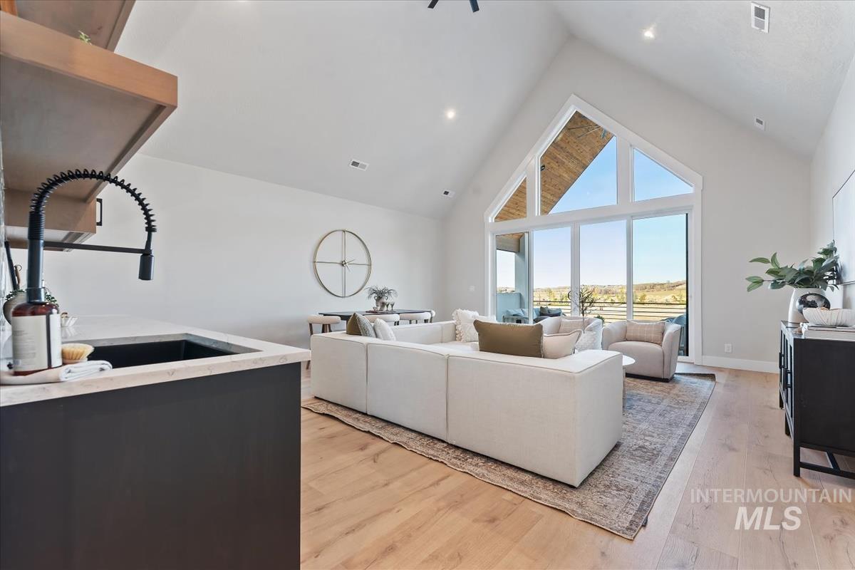 Living area with high vaulted ceiling and light wood-type flooring
