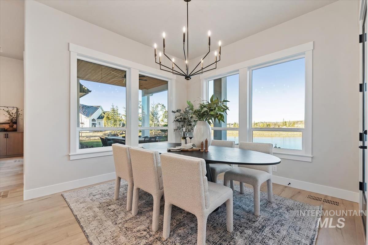 Dining area featuring light wood-style flooring, a water view, and a chandelier