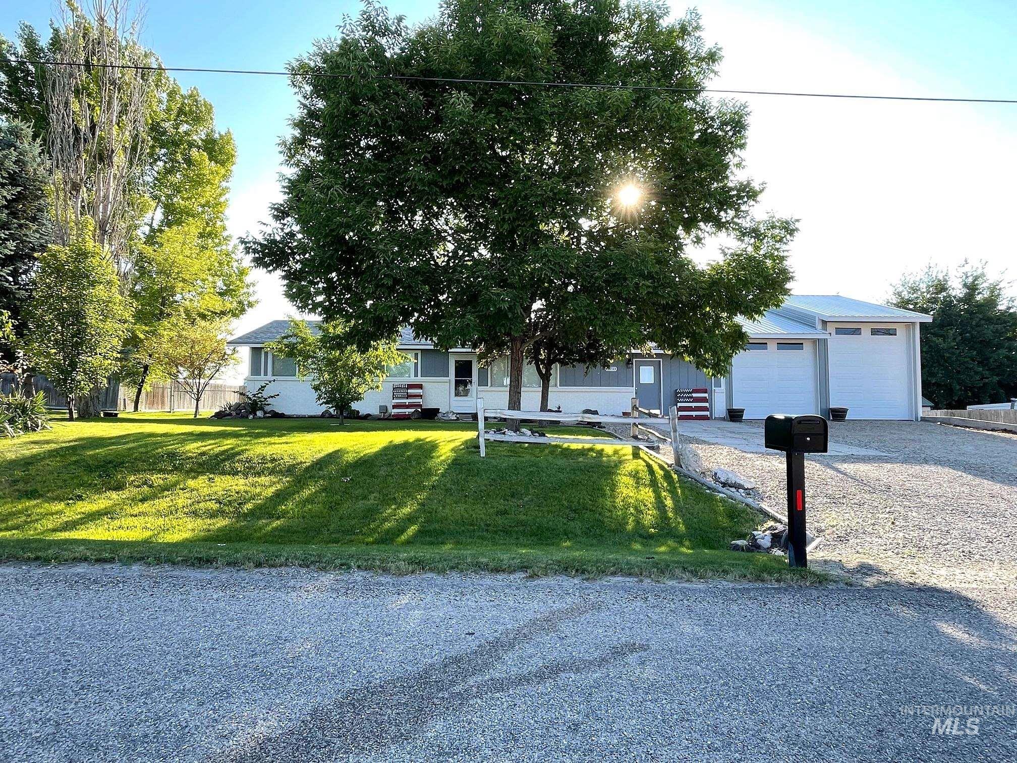 View of front facade with a front lawn, gravel driveway, and an attached garage